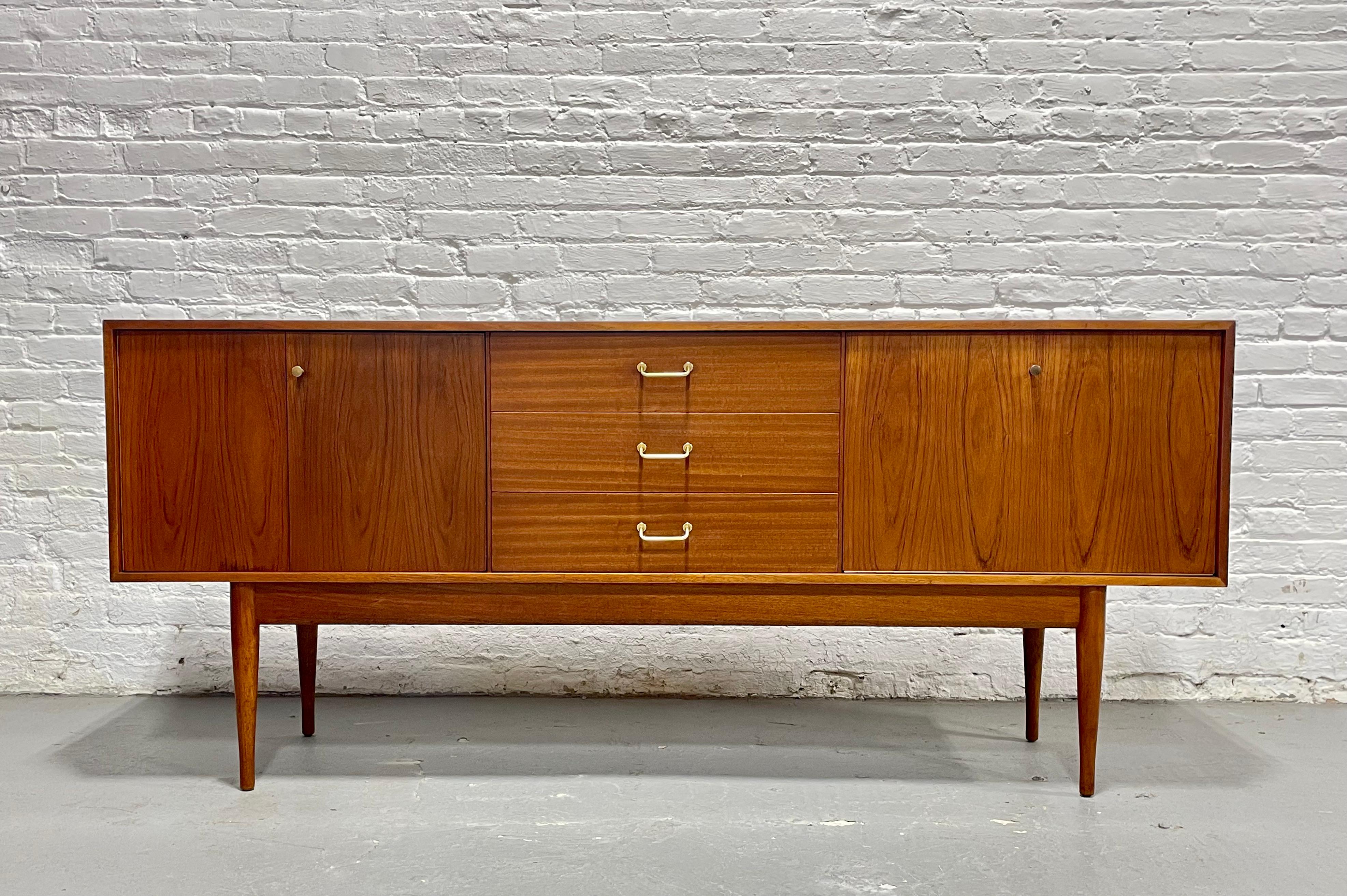 Danish Mid Century Modern Teak Credenza / Sideboard, c. 1960's. This minimalist yet highly functional design works beautifully as a media console, TV stand, or sideboard, featuring stunning wood grains, long sexy legs and golden drawer pulls which