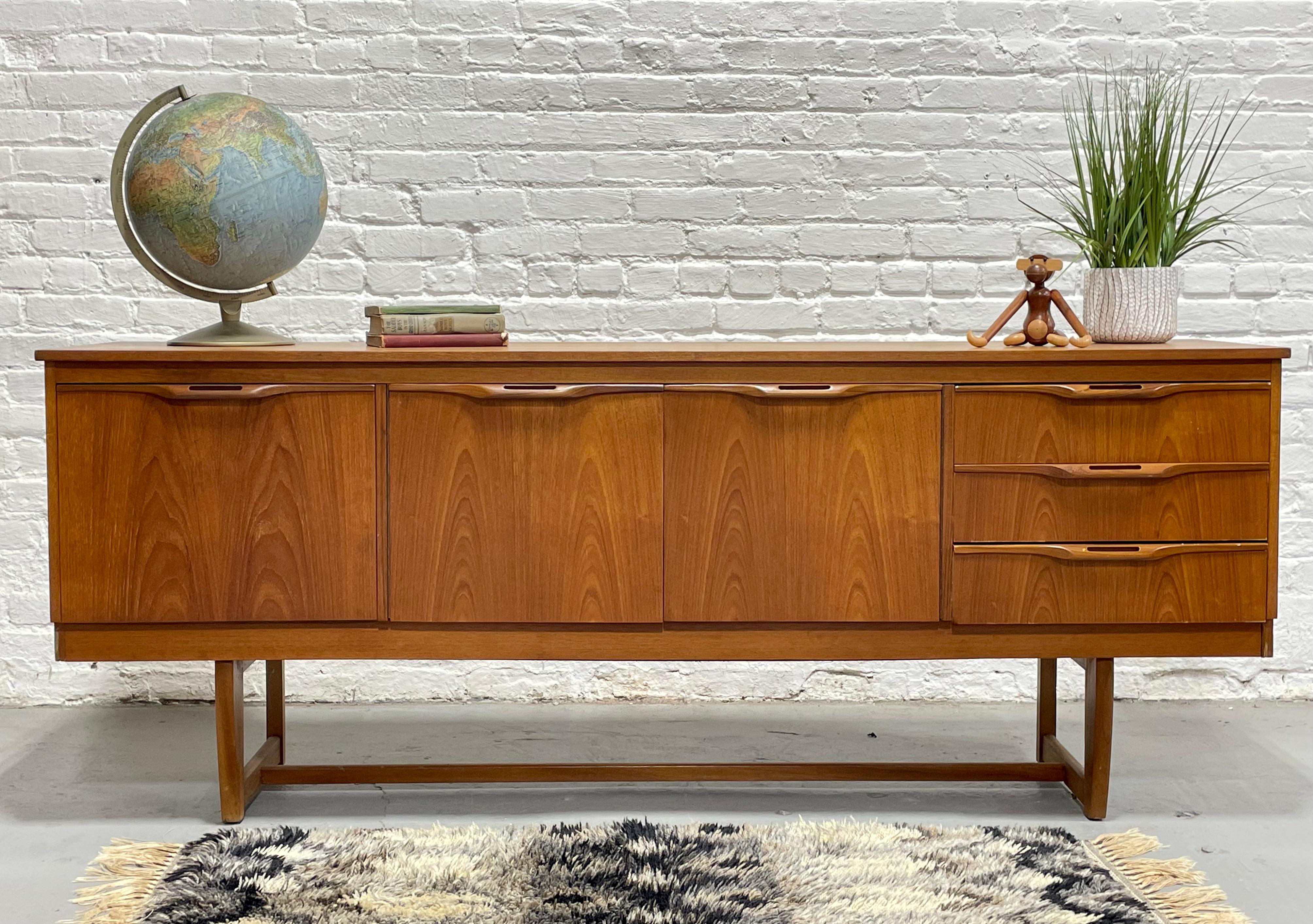 Mid Century Modern Teak Credenza / Media Stand by J. Sakol, Made in Scotlan, c. 1960's. This incredible sideboard features a drop down door, perfect for your media or as a bar. The two center doors open to a long shelf and there are three additional