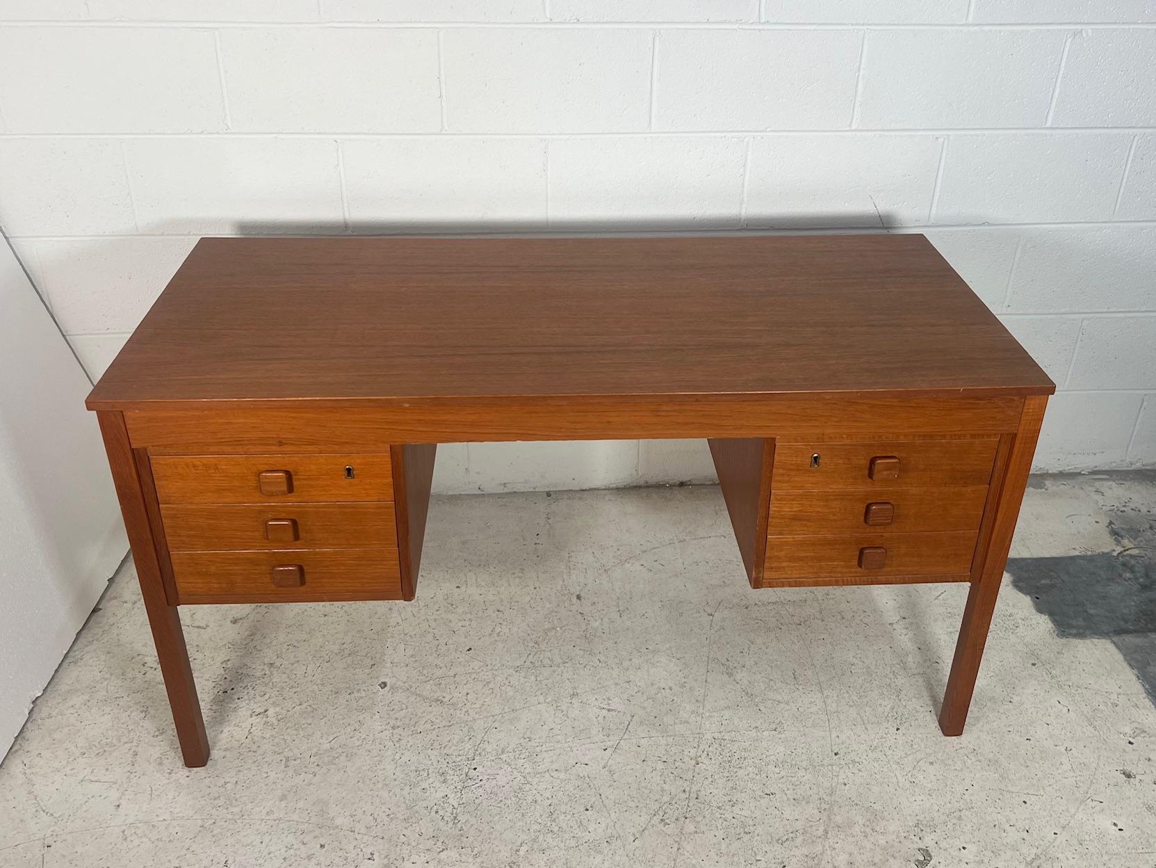 Fantastic mid-century teak veneer desk by Domino Mobler.
Featuring finished back and 6 clean drawers. 

Very good condition with only minor wear over all. Chip in the left corner of the back as shown in photos. Top drawer on the right side has some