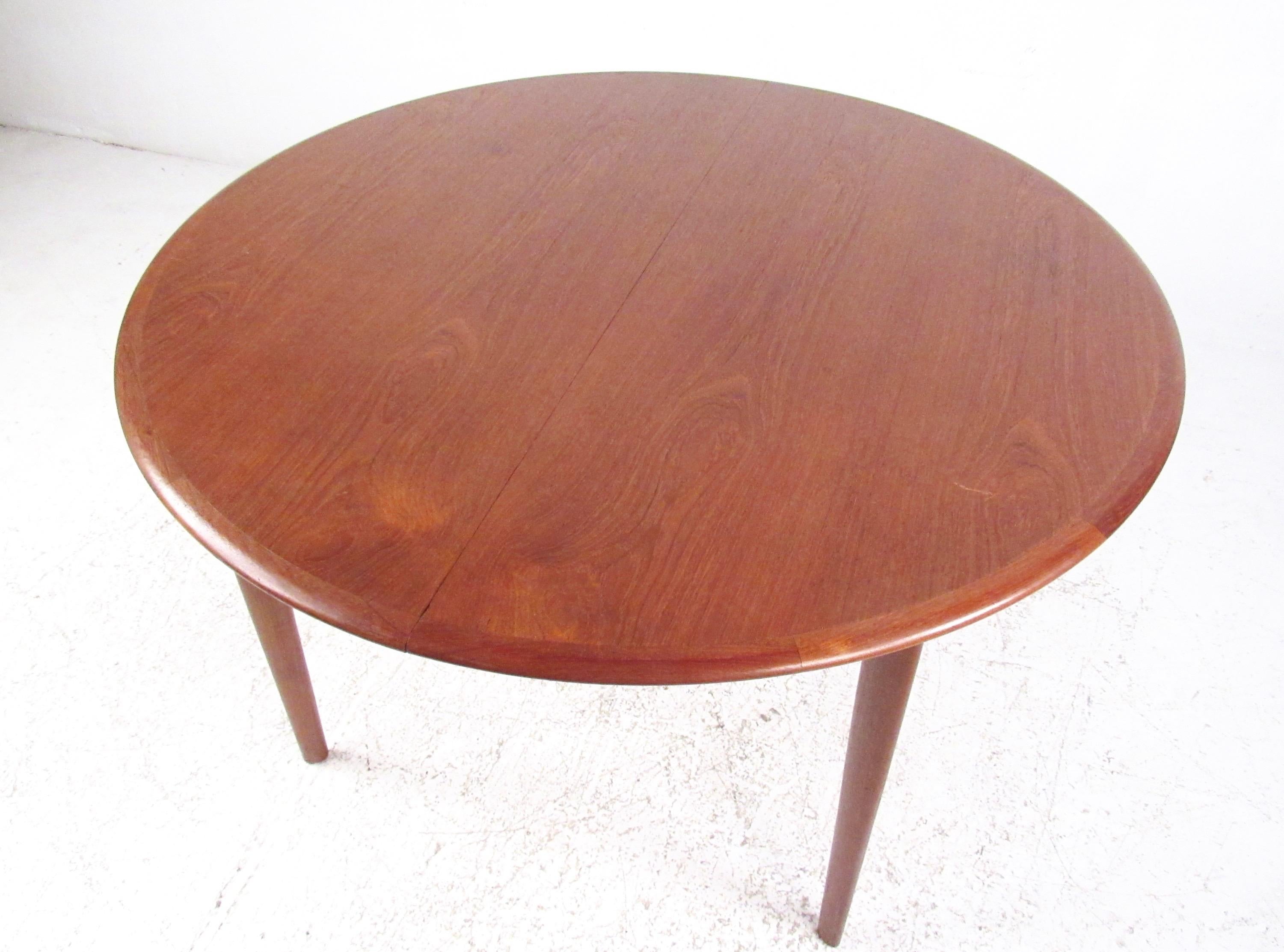 This beautiful vintage teak dining table features circular dining room design with a reddish teak finish. Easily expanded to include two additional 24 inch leaves, opening from 48 inches in diameter to 96 inches wide. This Scandinavian midcentury