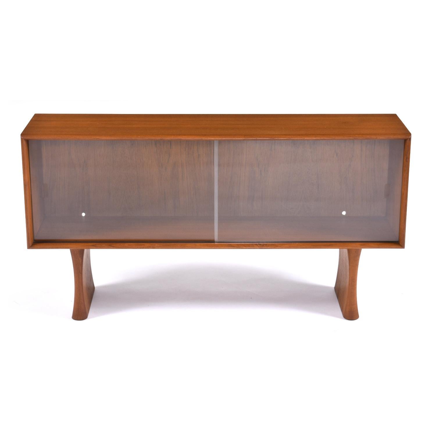 Lovely Mid-Century Modern Danish teak display cabinet with sliding glass doors. This unit can be used independently as a console, display case or media center. Alternatively, place this piece on top of your Danish teak credenza to create a two-piece