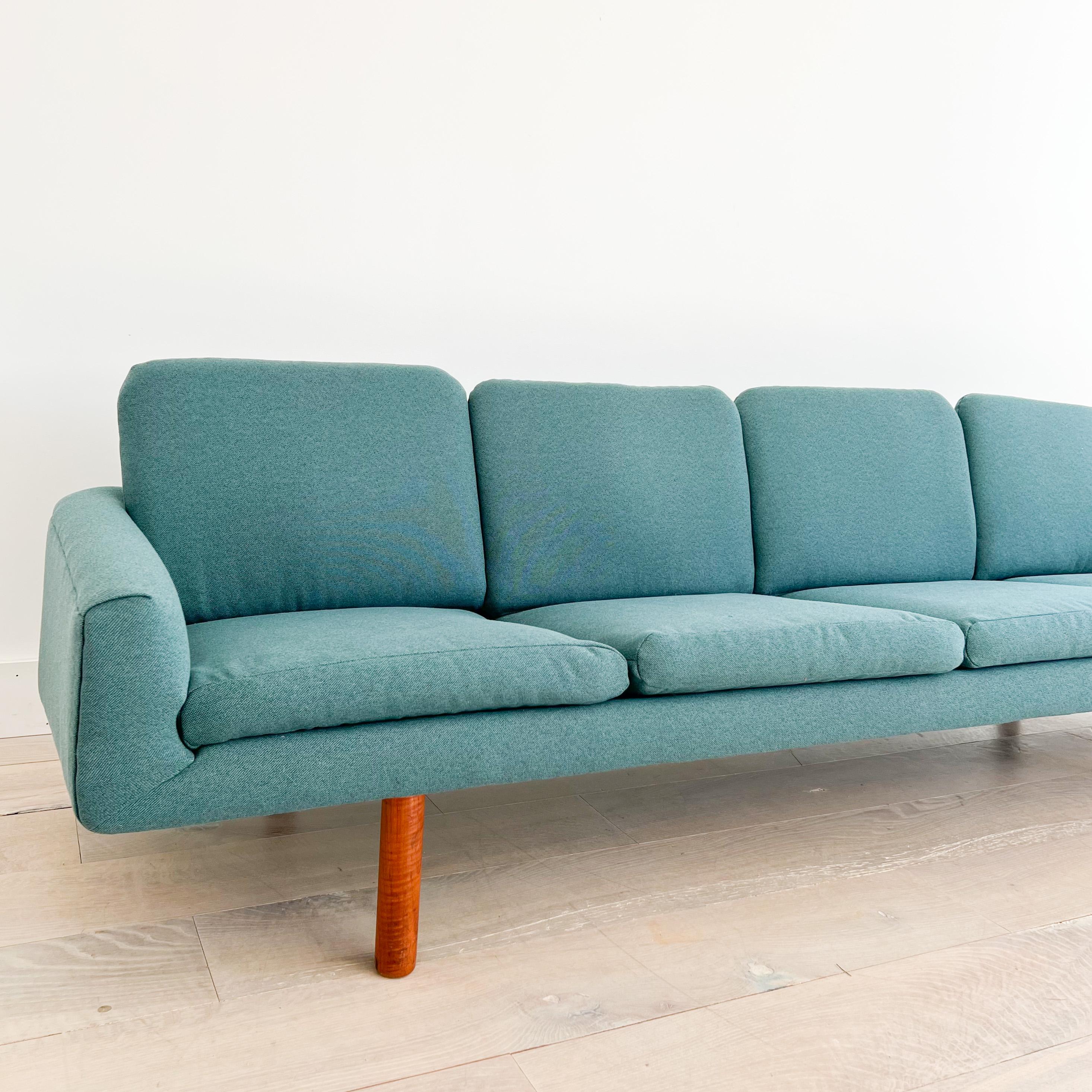 Mid century modern long 4 seater danish sofa with round teak legs. New foam and teal upholstery. Some light scuffing/scratching to the teak legs from age appropriate wear.