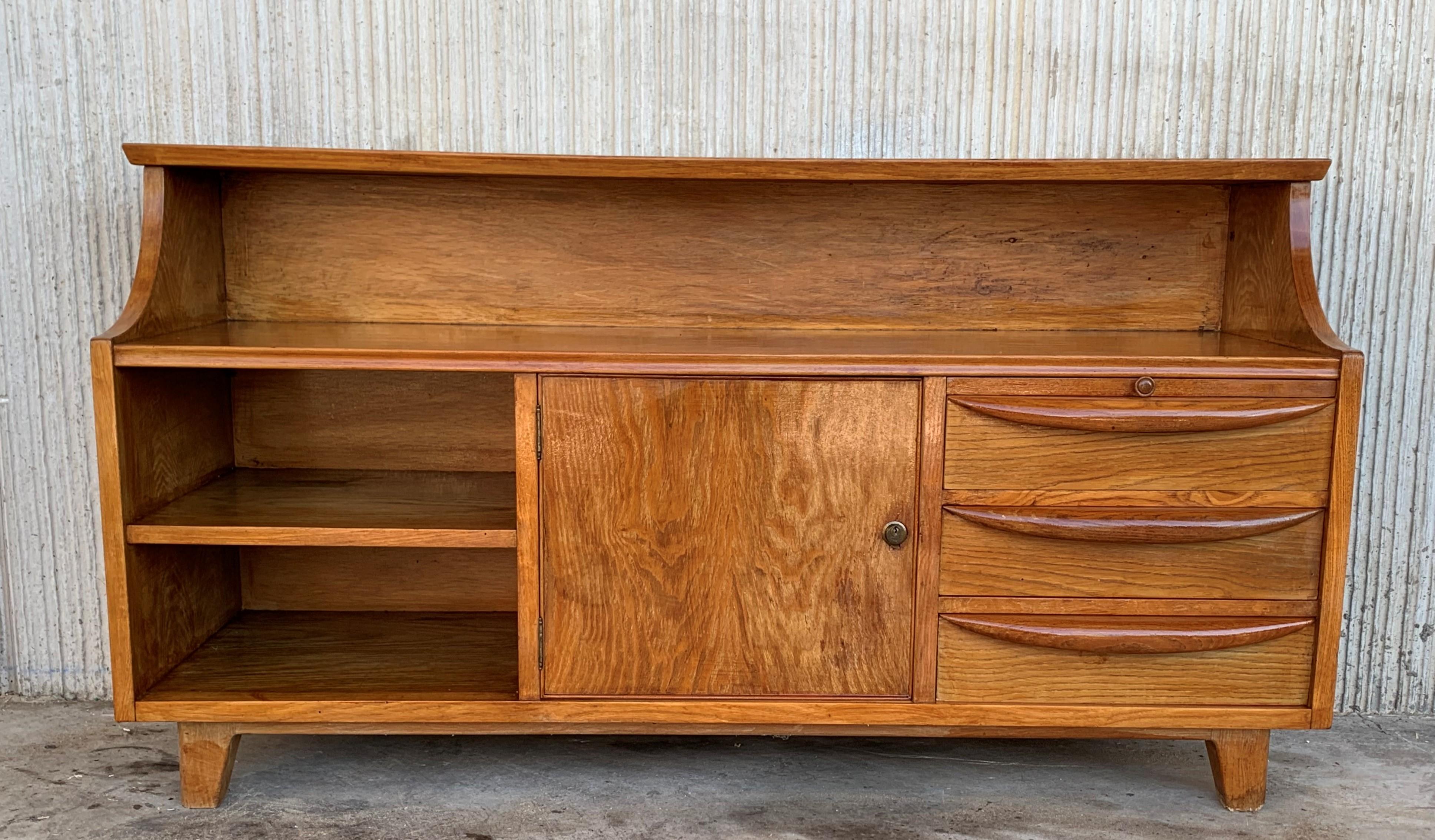 Mid-Century Modern small chest of drawers in teak manufactured circa 1960s. This piece includes three low compartments in the low part, one with three dovetailed drawers with sculpted handles and one tray, one compartment with door and the last with