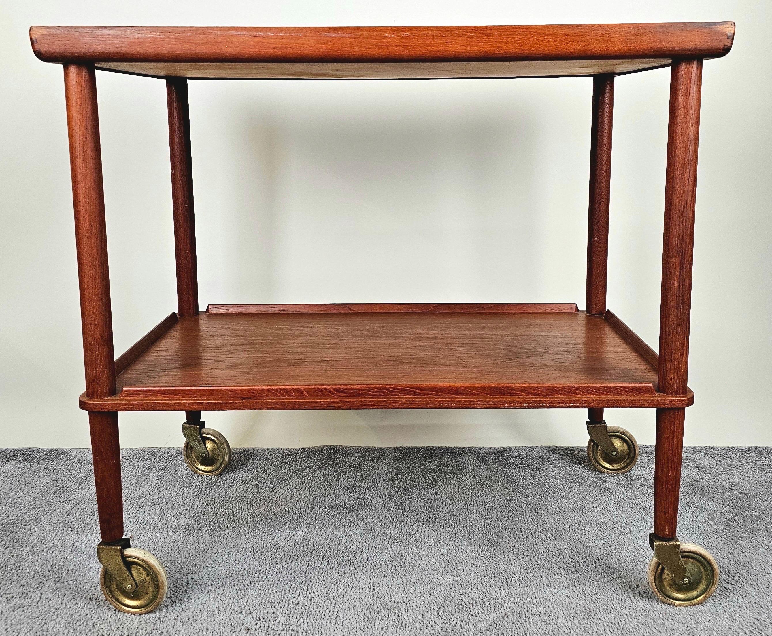 Un carrito de bar rodante danés moderno de mediados de siglo atribuido a los icónicos diseños de Poul Hundevad ( danés 1917 -2011), que refleja la impecable artesanía y la elegancia minimalista del diseño escandinavo. Construido con teca rica y