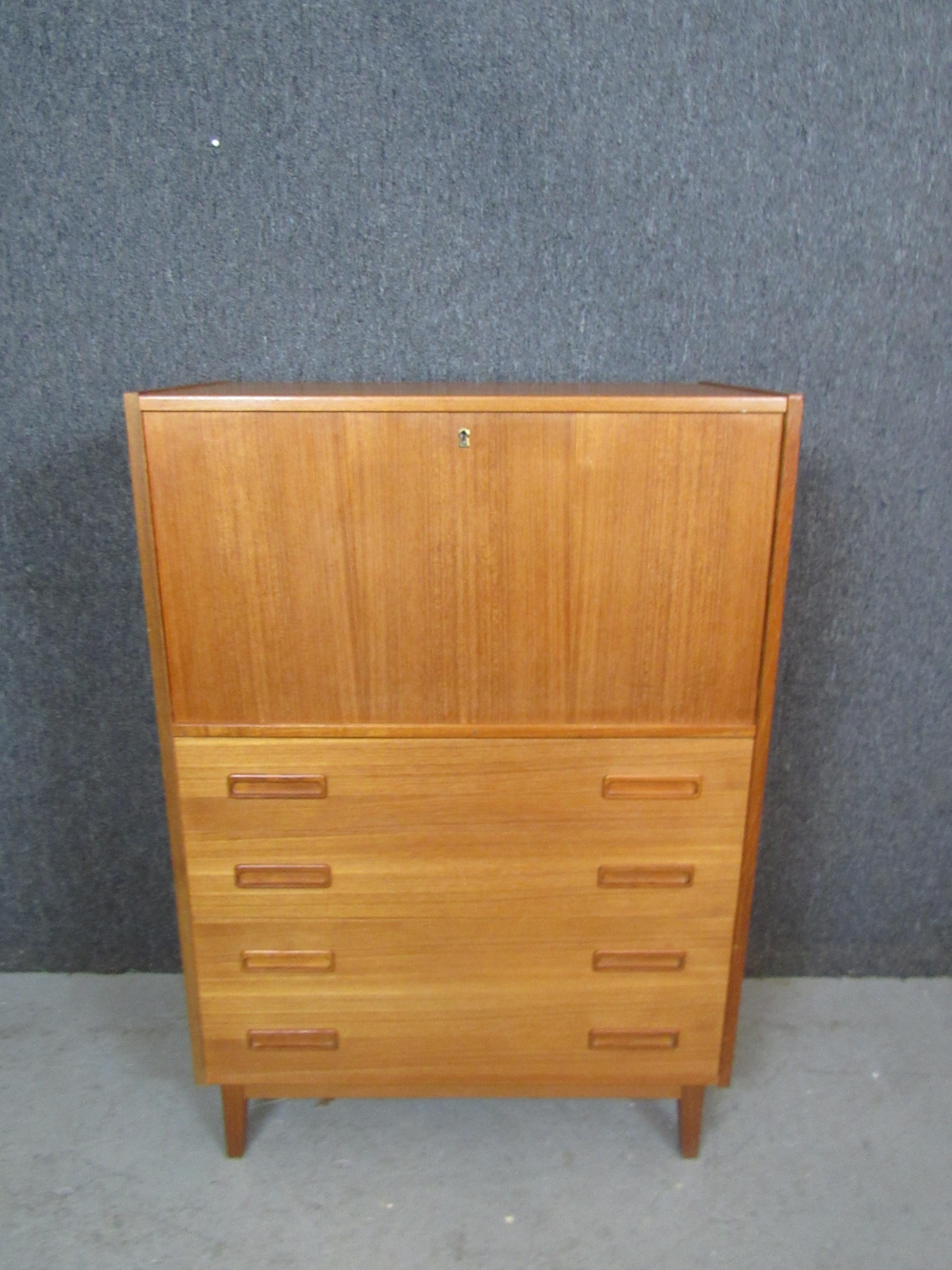 Add functional and stylish storage to your workspace with this fantastic vintage Danish teak wood secretary desk. The drop down door opens up to reveal an ample desktop with built in cubbyholes and drawers to help cut down on clutter. Four