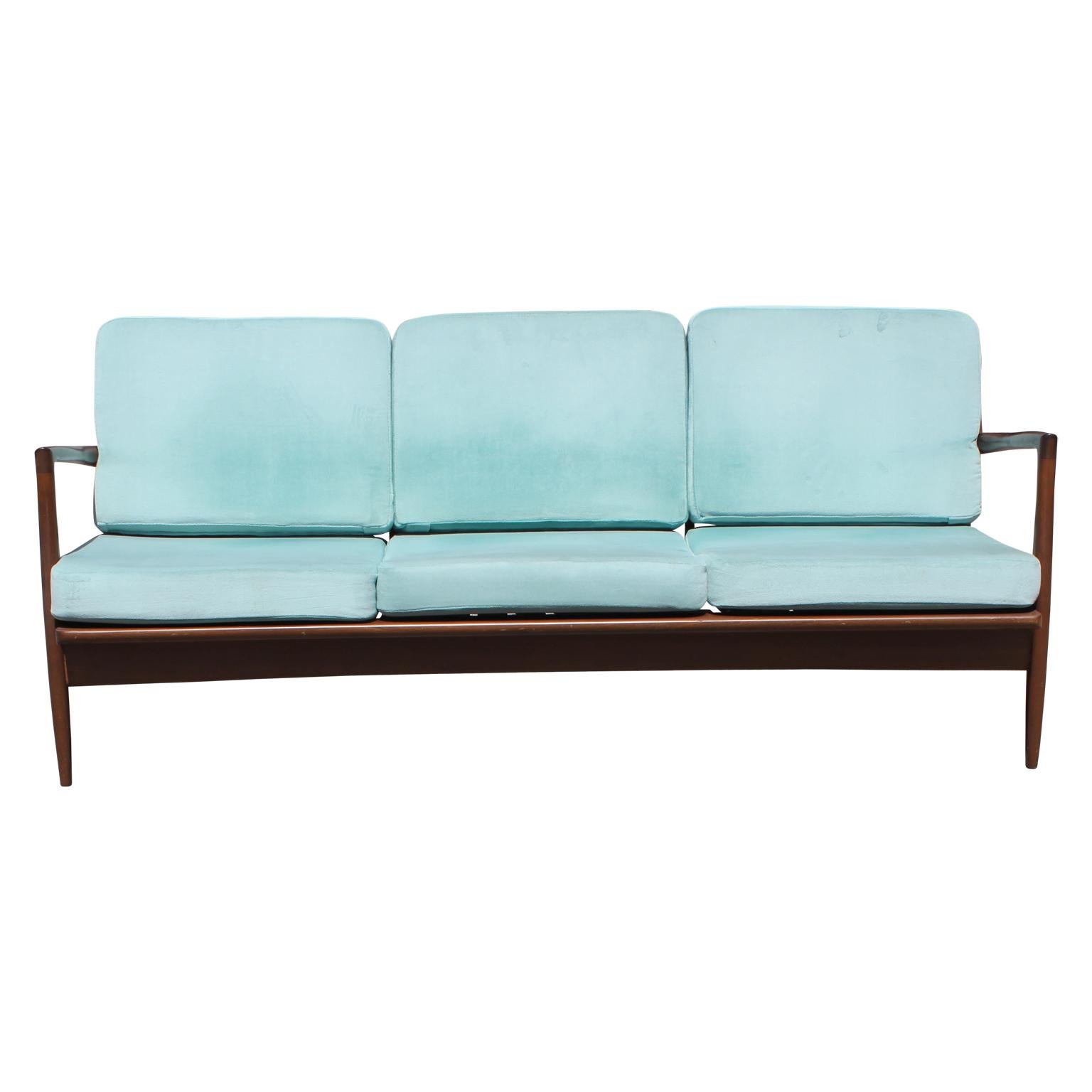 Sleek Mid-Century Modern settee made from teak wood in the Danish style. This sofa is by Ib Kofod-Larsen for Selig. The customer can reupholster the pillows COM.