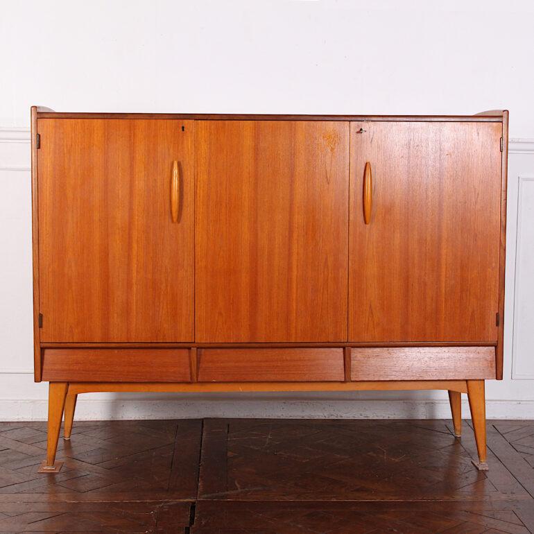 A Mid-Century Modern Danish teak sideboard or credenza with ample storage in three enclosed cabinets above three drawers and raised on splayed turned tapering legs. C. 1965.
