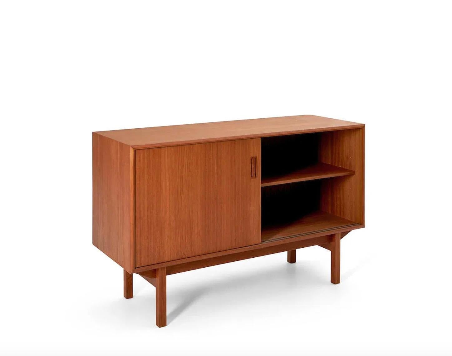Aparador escandinavo moderno danés de mediados de siglo en madera de teca al estilo de Børge Mogensen. Las puertas correderas se abren al interior con (2) estantes ajustables o extraíbles, (1) a cada lado. Fabricado en Dinamarca hacia 1960. Se