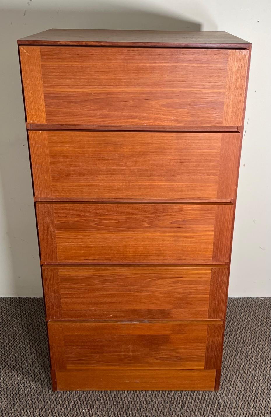 This is a teak tall boy dresser with 5 drawers by Vinde Mobelfabrik. Made in Denmark. Original stamp at the back. Very nice condition with minimal wear. Small chip on one side at the bottom. Some scratches on the top. Some small marks and stains