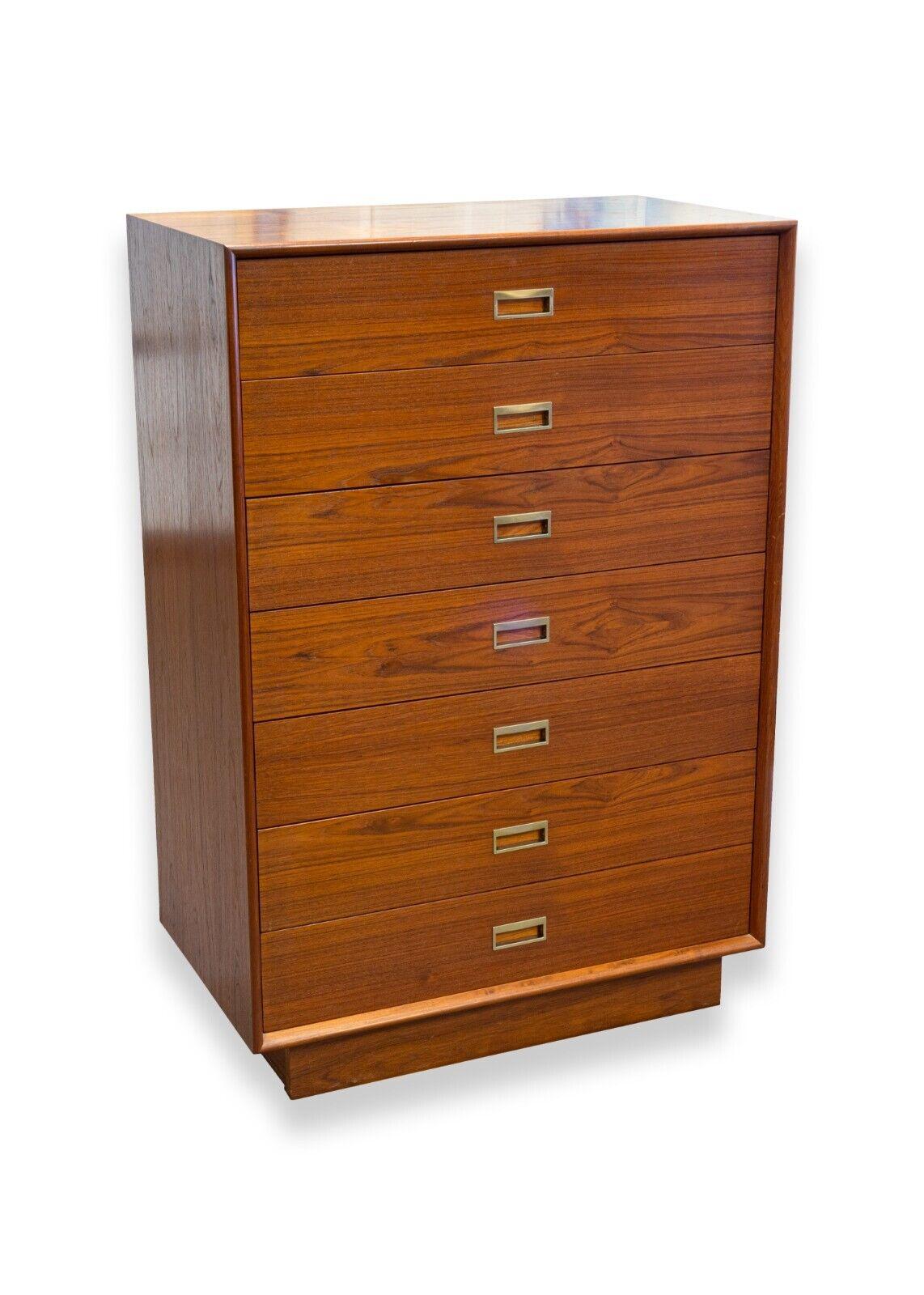 A mid century modern Danish teak wood highboy dresser. A wonderful highboy dresser of Danish origin. This piece features a gorgeous teak wood construction with brass handles, 7 equally sized sliding drawers, and an unfinished back. This piece is in