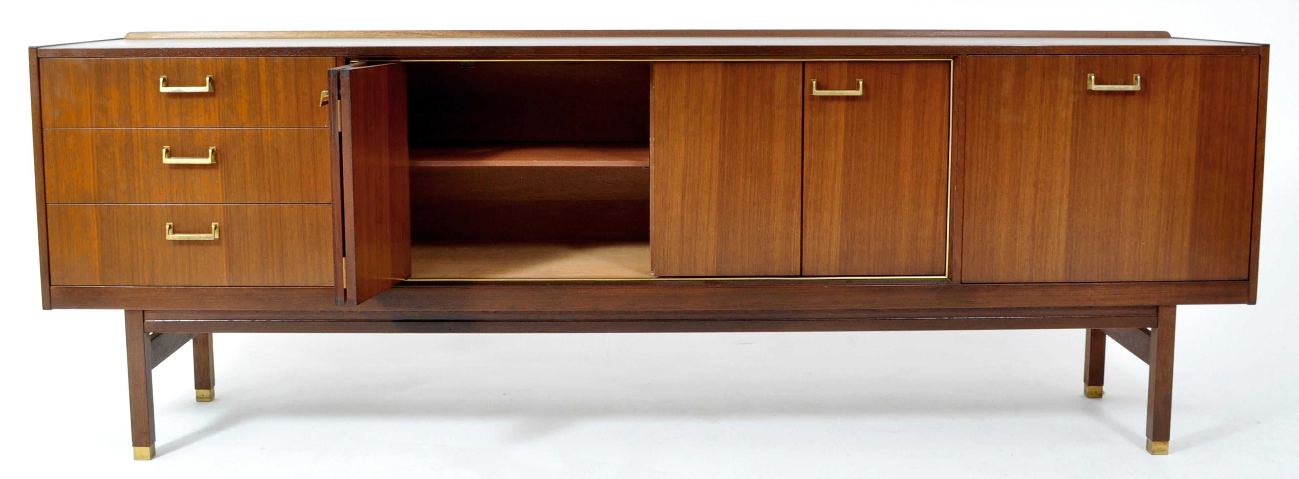 Mid-Century Modern Danish style credenza in Walnut by G Plan, 1960s, designed by IB. Kofod Larsen. The credenza having a central cupboard with 'concertina doors' and enclosing a divided chamber with a single shelf throughout. To the right a fall