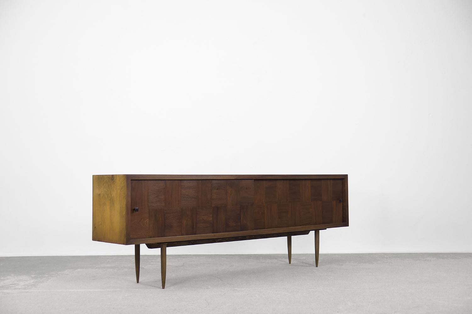 This high sideboard was made in Denmark during the 1960s. It has been finished in the shade of walnut wood, where between the main color are caramel-colored threads. Additional aesthetic values were obtained due to the rare, transient arrangement of