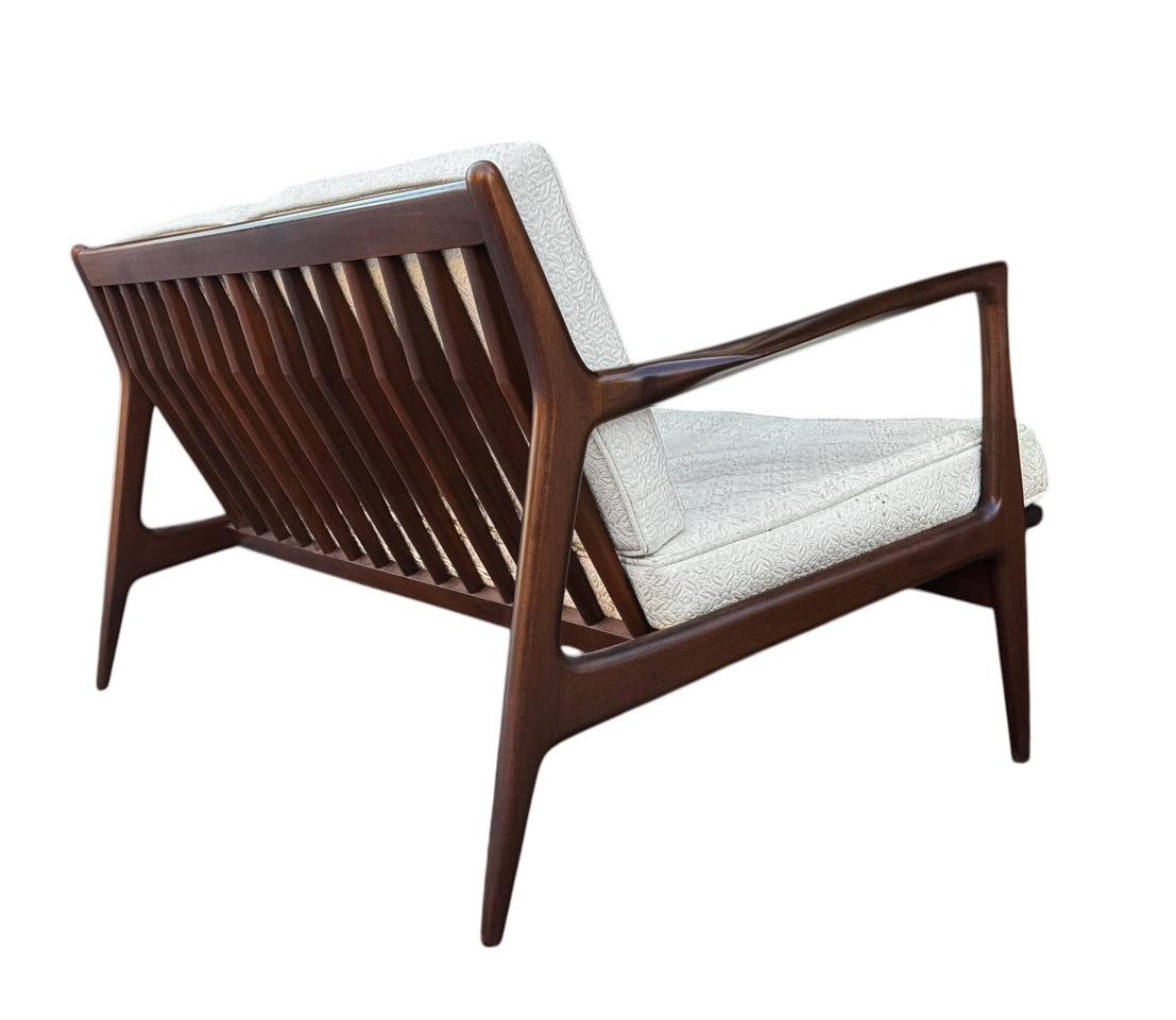 A beautifully designed and crafted sofa by Ib Kofod Larsen for Selig circa 1960's. It features a solid walnut frame and original upholstery. Manufacturers stamp is present. Fabric is original and in poor condition. Seat straps were redone. 
