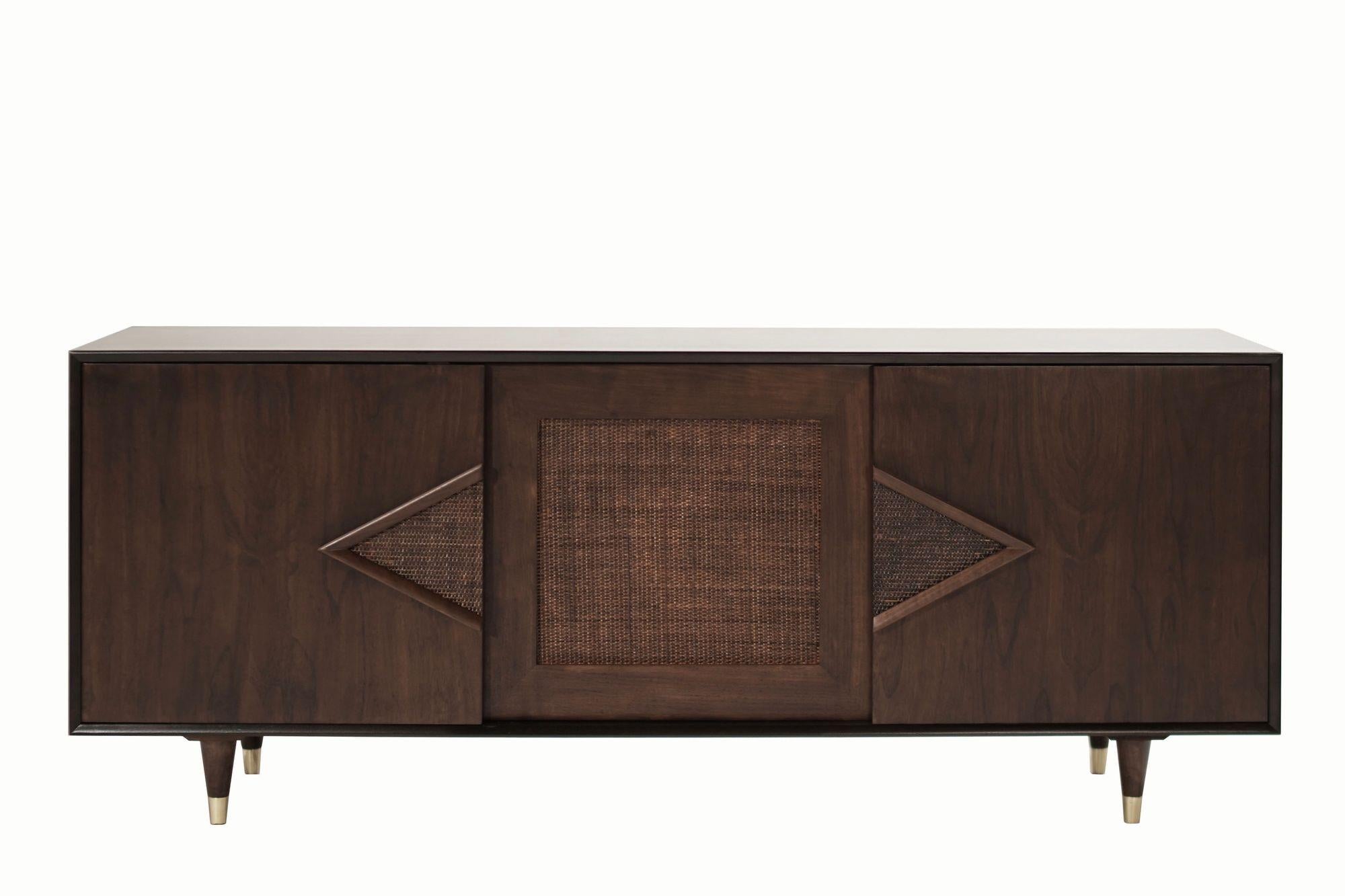 A very handsome credenza or sideboard executed in dark walnut, completely restored, circa 1950-1950. It features three sliding doors with cane details and brass sabots, each door opens up to reveal shelving, there's also a silverware drawer in the
