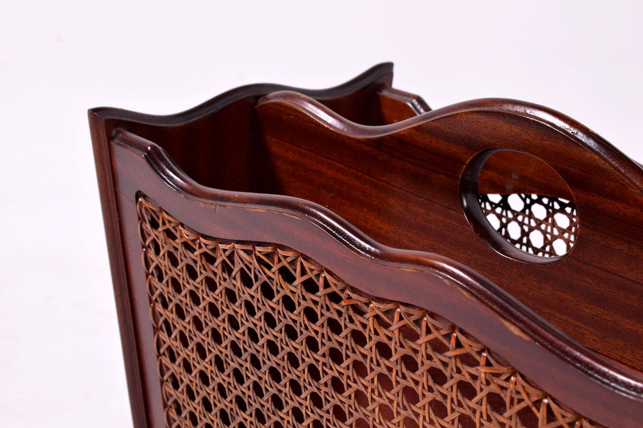 This image captures a mid-century magazine rack, an elegant storage solution that combines the rich, warm hues of solid mahogany wood with the intricate, geometric patterns of Vienna straw. The mahogany presents a polished finish, reflecting a deep