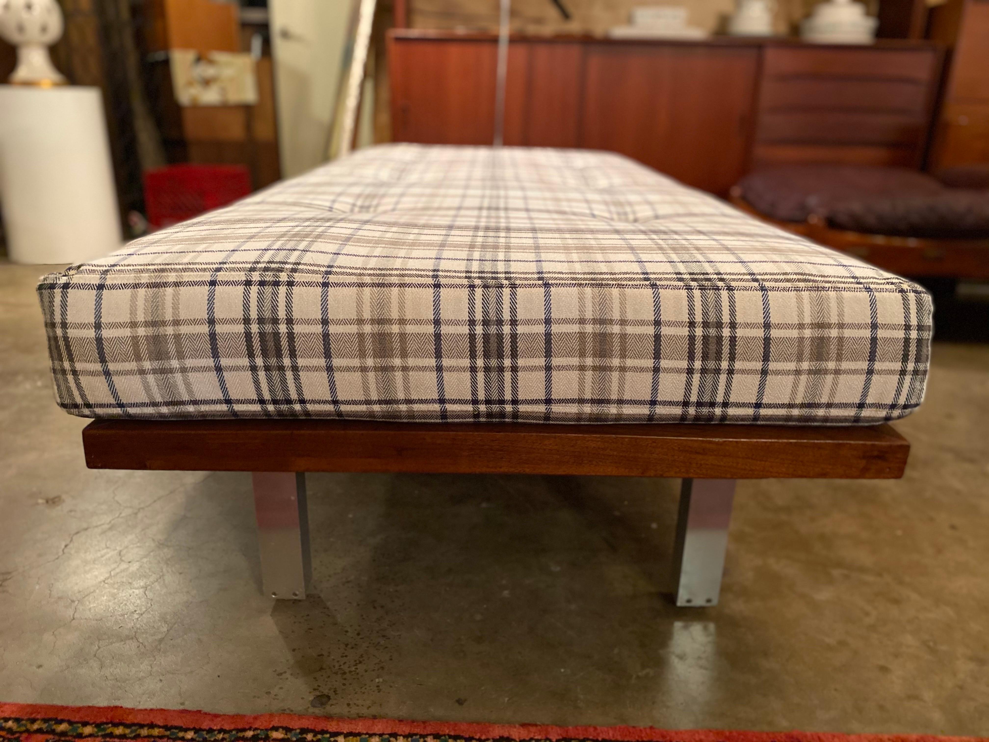 Mid-Century Modern daybed has been newly reupholstered with a neutral plaid fabric. The platform base has been newly strapped and is made of walnut with aluminum feet. This modern daybed is a great addition to any space and is great for lounging.