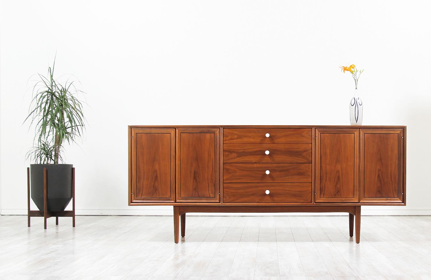 Mid-Century Modern credenza designed by Kipp Stewart & Stewart MacDougall for Drexel’s “Declaration” line in the United States, circa 1950s. This credenza features a solid walnut wood frame accented with the original signature brass & porcelain