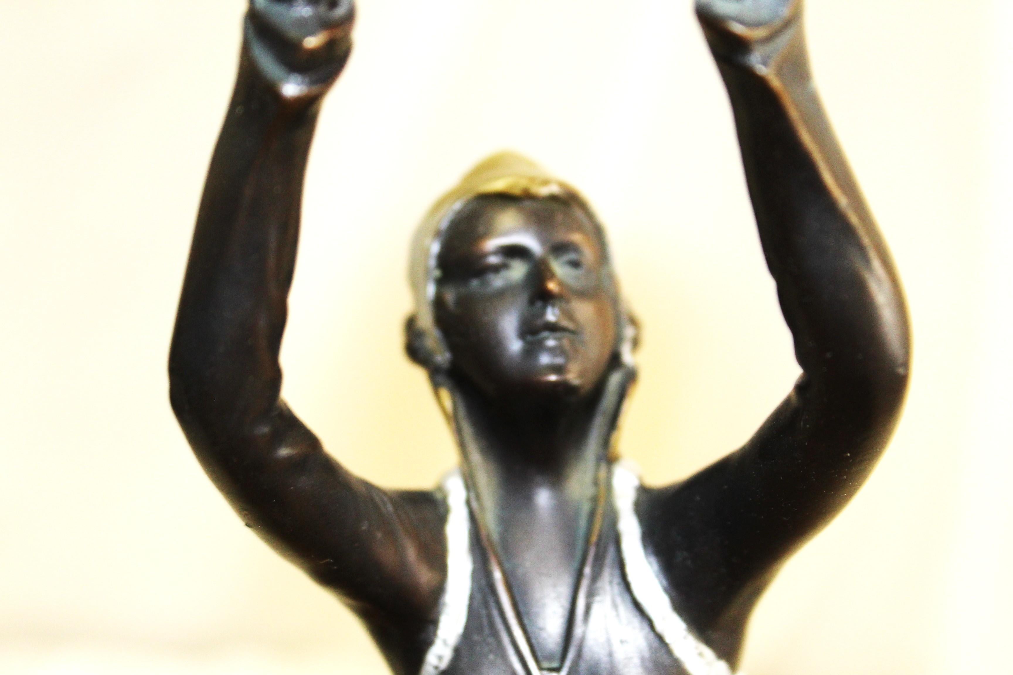 A bronze cast figurine of a Girl standing holding a ball above her head . Made after a well known Art Deci Artist ( Preiss) . Standing on a round marble base 4 1/2