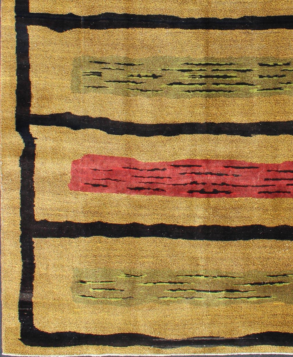 Attributed to the famous Turkish rug designer, Zeki Müren, this Mid-Century modern design rug displays a sandy-tan background. The rug features five black outlined boxes with shades of green and red alternate with hints of black. Simple yet modern.