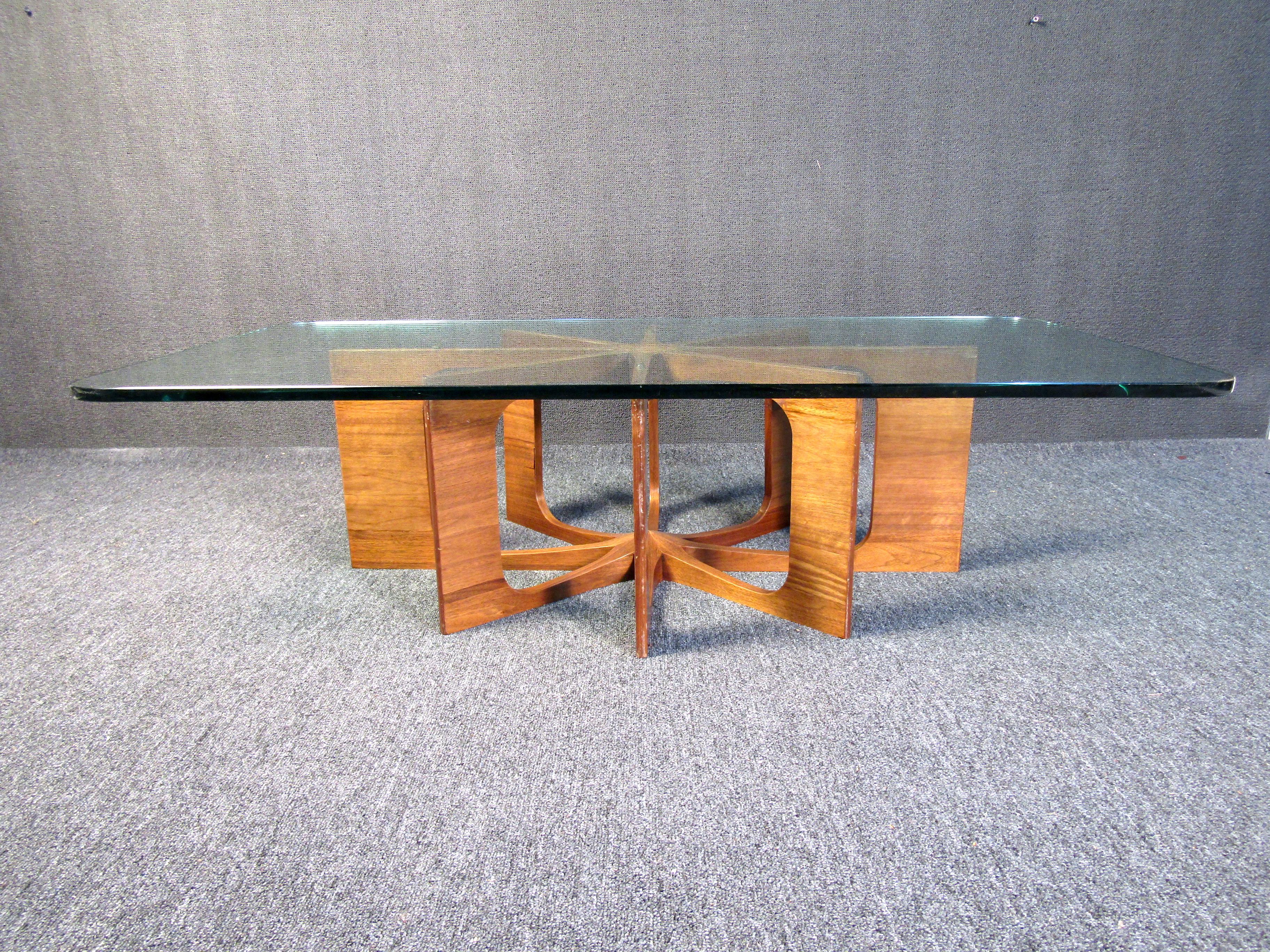 This beautiful designer coffee table shows off an elaborate walnut base through a clear glass top. Full of Mid-Century Modern style, this table is sure to attract attention in any living room or home. Please confirm the item location (NY or NJ).