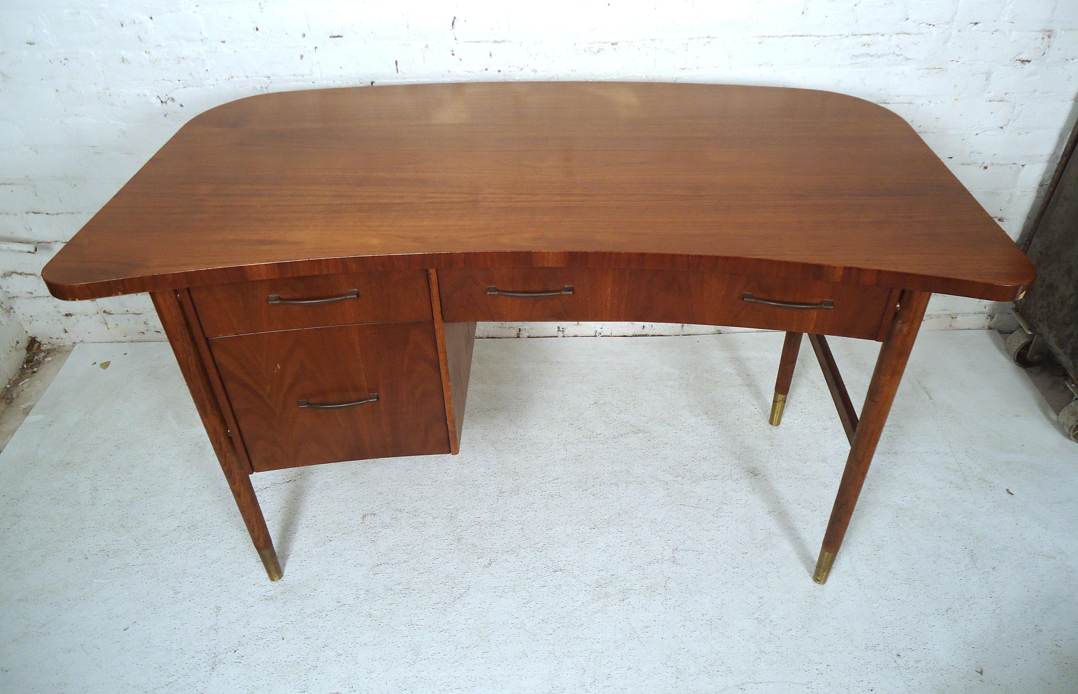This unusual vintage modern desk features a bowed front, three drawers, brass pulls, round legs, rich walnut grain desk and upholstered chair.
Chair dimensions: 19