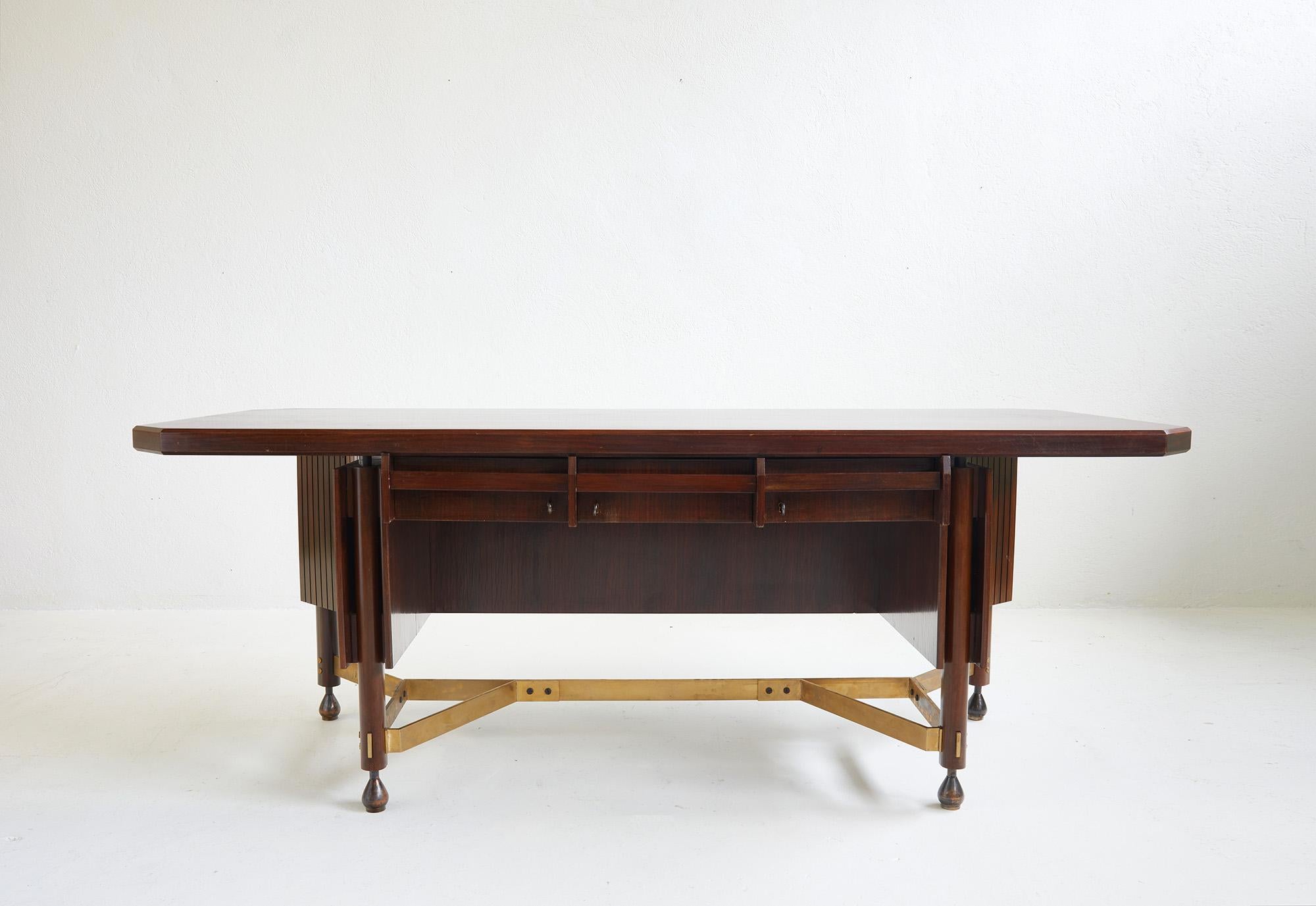 Rara e imponente scrivania direzionale della metà del secolo scorso attribuita a Claudio Olivieri e Renato Angeli. Italia anni '50.

La scrivania è interamente realizzata in legno scuro laccato e ottone massiccio. Il piano rettangolare presenta