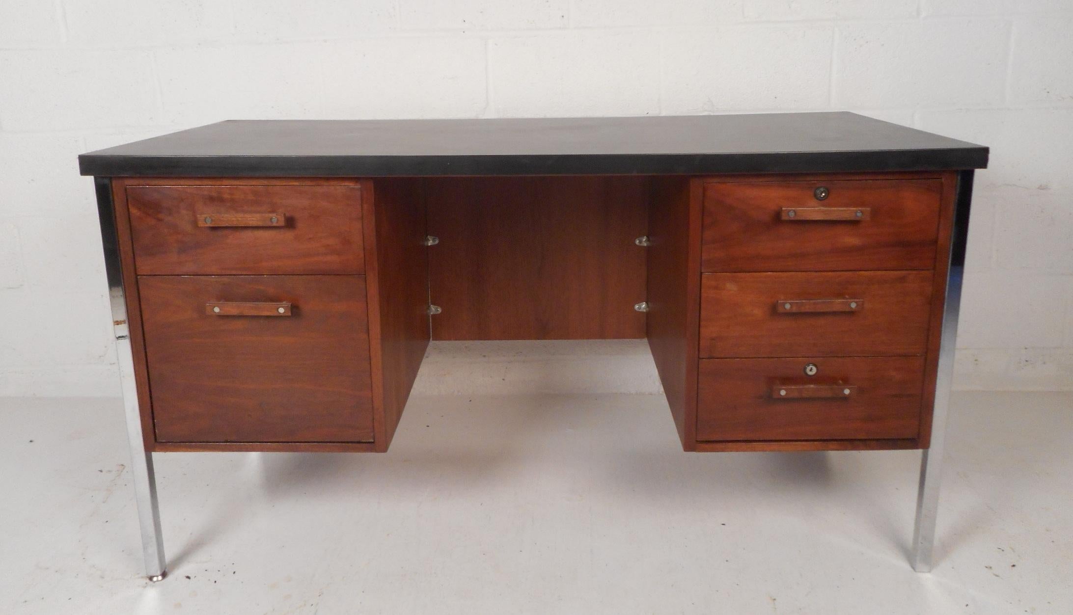 This stunning vintage modern desk features a black painted wood top and chrome legs. A sleek design with a vast amount of storage space within its five hefty drawers. Quality construction with elegant walnut wood grain and unique drawer pulls adding