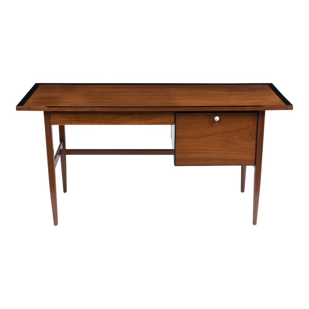 Mid-Century Modern executive desk has been professionally restored, is made out of Walnut wood, and features a sleek design. Its been newly stained in a walnut color with ebonized molding accents and a lacquered finish. This piece also has a