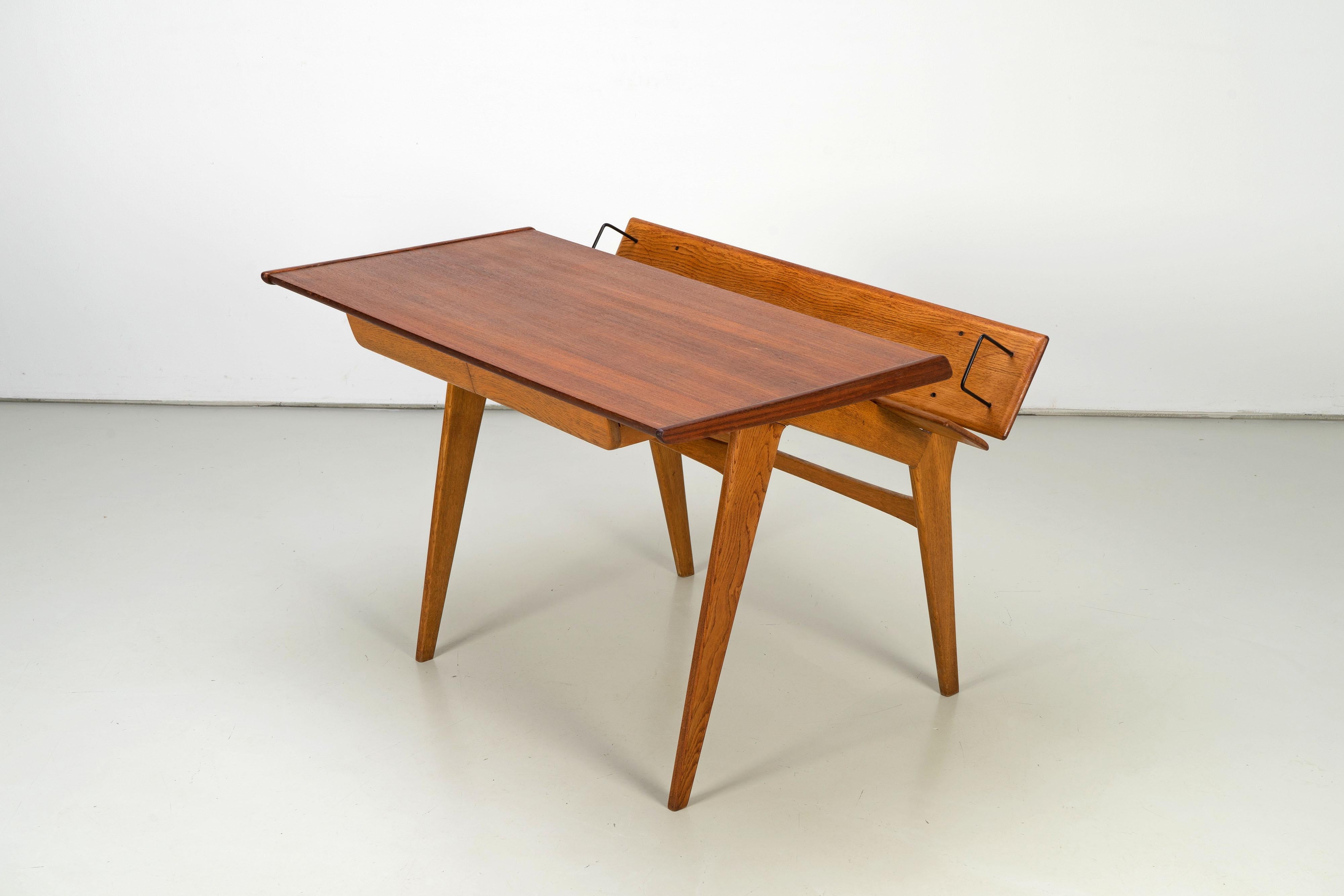 A very rare writing desk made from teak and oakwood from the 1950s. The desk is excellently manufactured and features an extraordinare design. A book rack with built-in bookends floats behind the tabletop.