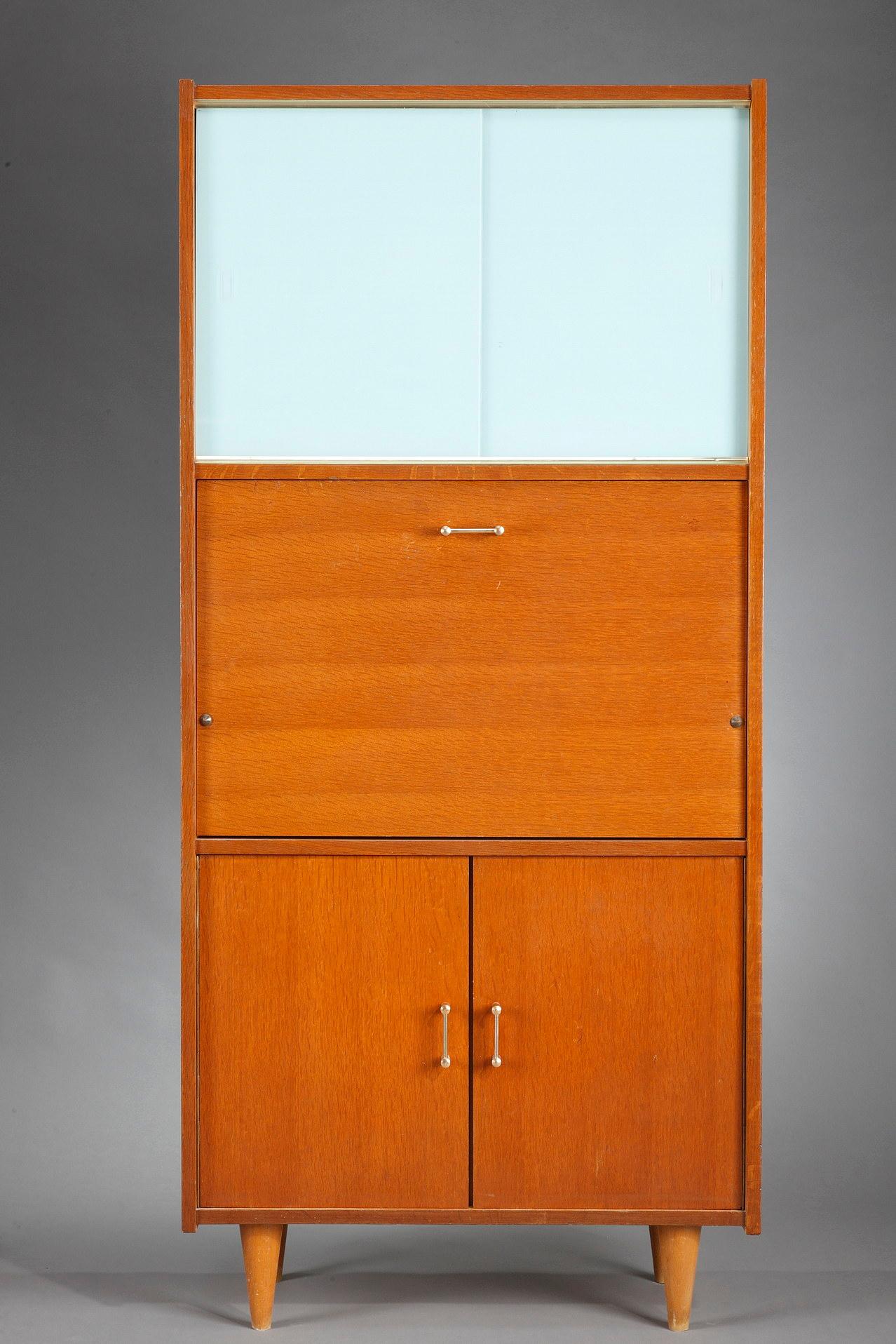 This is a Mid-Century Modern secretary desk in teak veneer from the 1960s. In the lower part, two doors open onto a shelf and a panel drops to reveal a desk space. The upper part opens with two tinted sliding glass doors. The whole rests on four