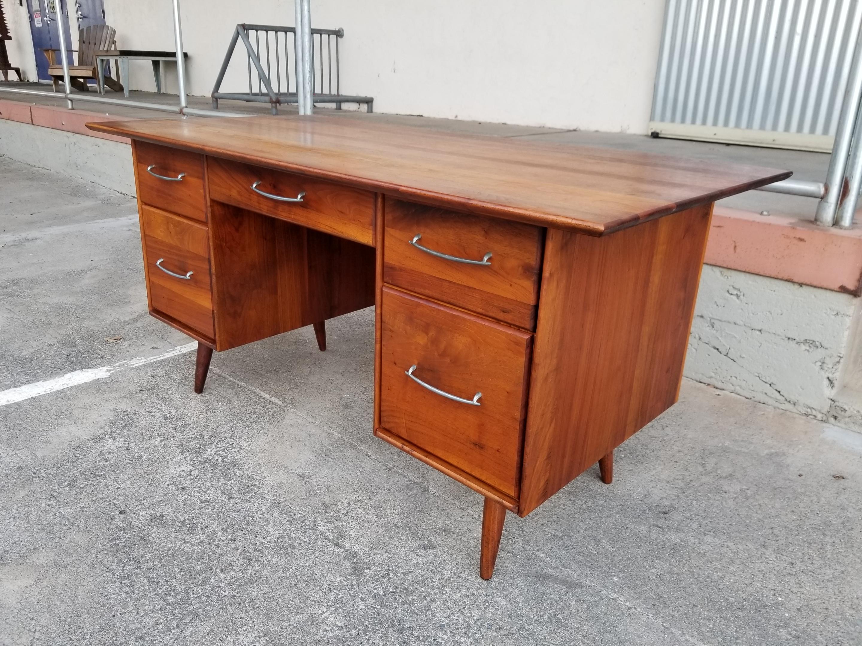 Rarely do you see a Mid-Century Modern piece made with solid walnut. Beautiful glow and depth to the solid planked walnut finish. Class peg-leg and over-hung top detail. Ample storage and surface work space as top surface measures 30