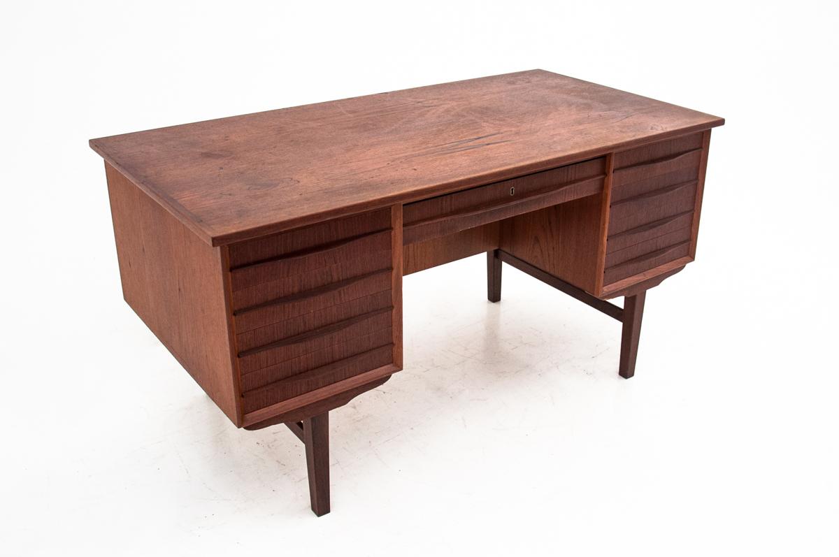This exceptional desk was made of teak wood in the turn of the 1960s and 1970s in Denmark. It is Mid-Century Modern desk. It has 7 spacious drawers and a shelf at the back. Maintained in good condition, the desk has been renovated.