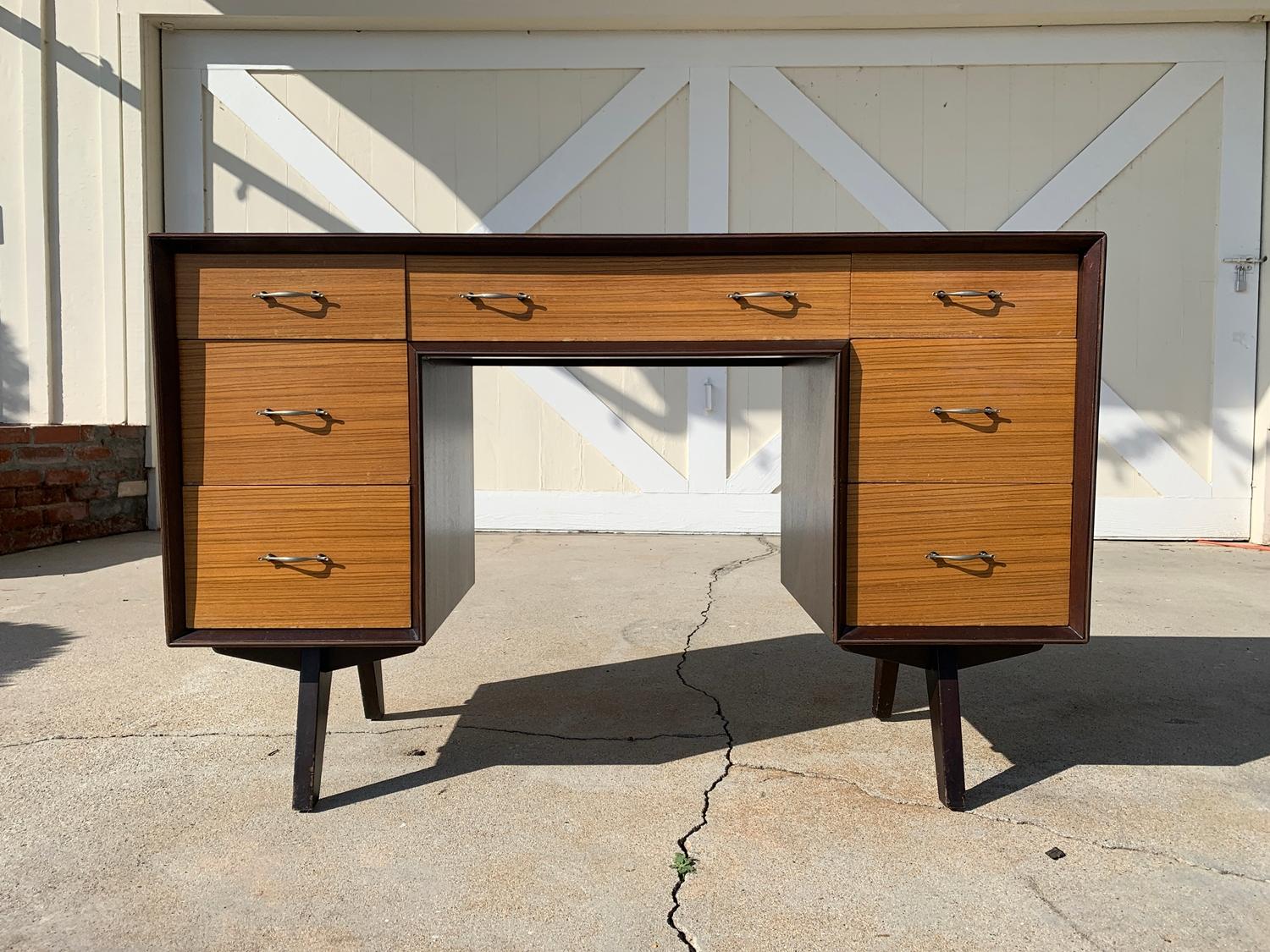Beautiful compact desk from the 1940s-1950s with 7 drawers and beautiful arquitectural lines.
The piece has beautiful joinery on the drawers and legs, the contrast in colors of the drawers and rest of the desk is really quite stunning.

The piece