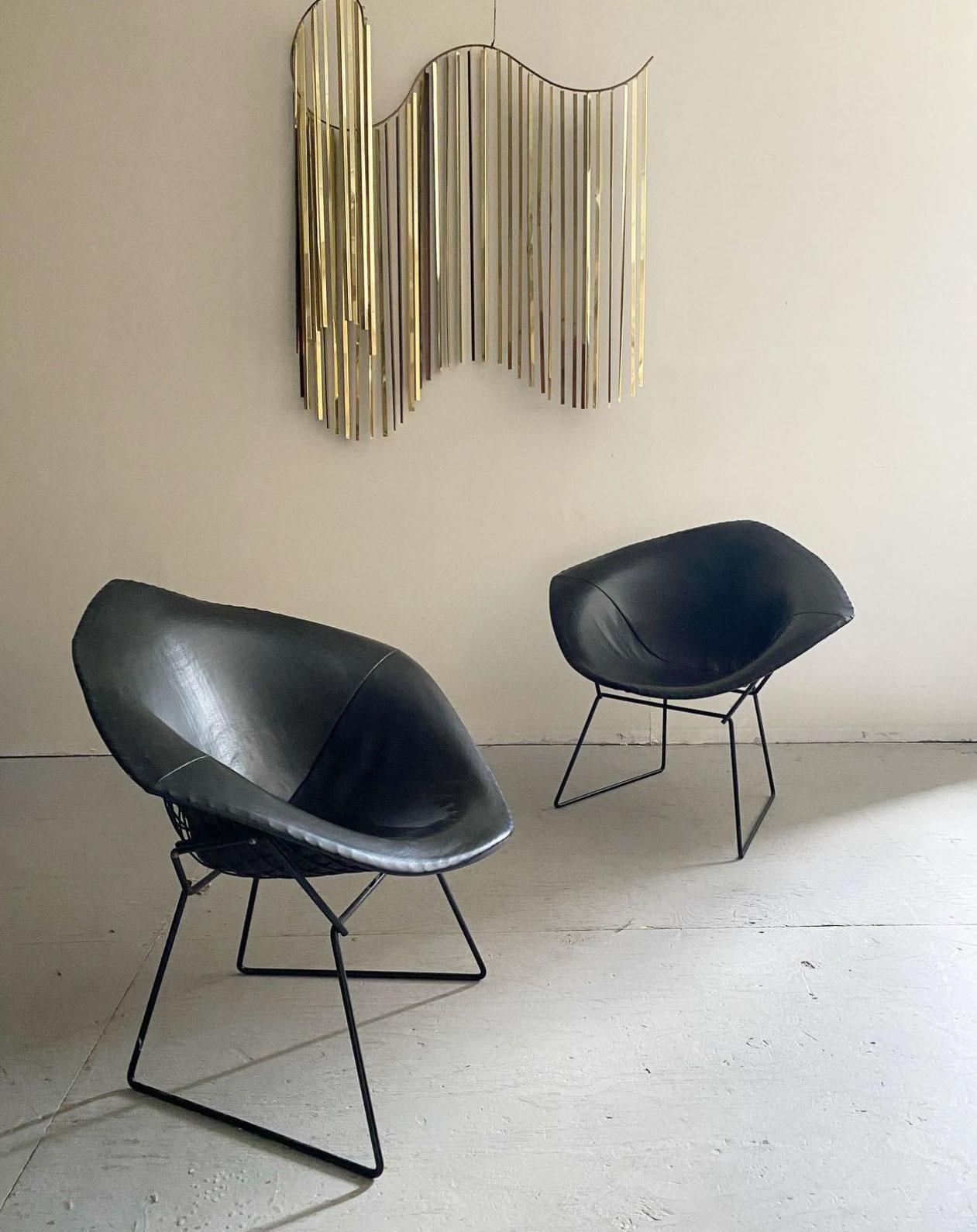 Mid-Century Modern “Diamond” Chairs Designed By Harry Bertoia For Knoll, circa 1960s. This early pair of Diamond chairs feature original fully upholstered black leather covers. Both chairs have two early manufacturer labels on the underside with