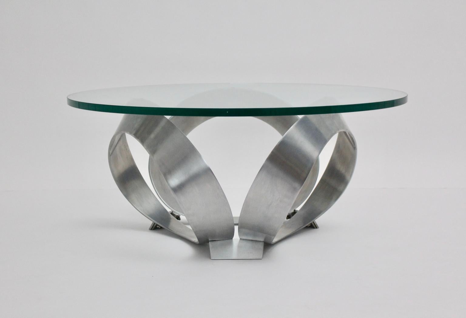 Space Age vintage table basse diamant comme a été conçu par Knut Hesterberg et exécuté par Ronald Schmitt 1960s Allemagne.
Une belle table basse avec trois anneaux en aluminium et surmontée d'une plaque de verre de 2 cm d'épaisseur avec bord