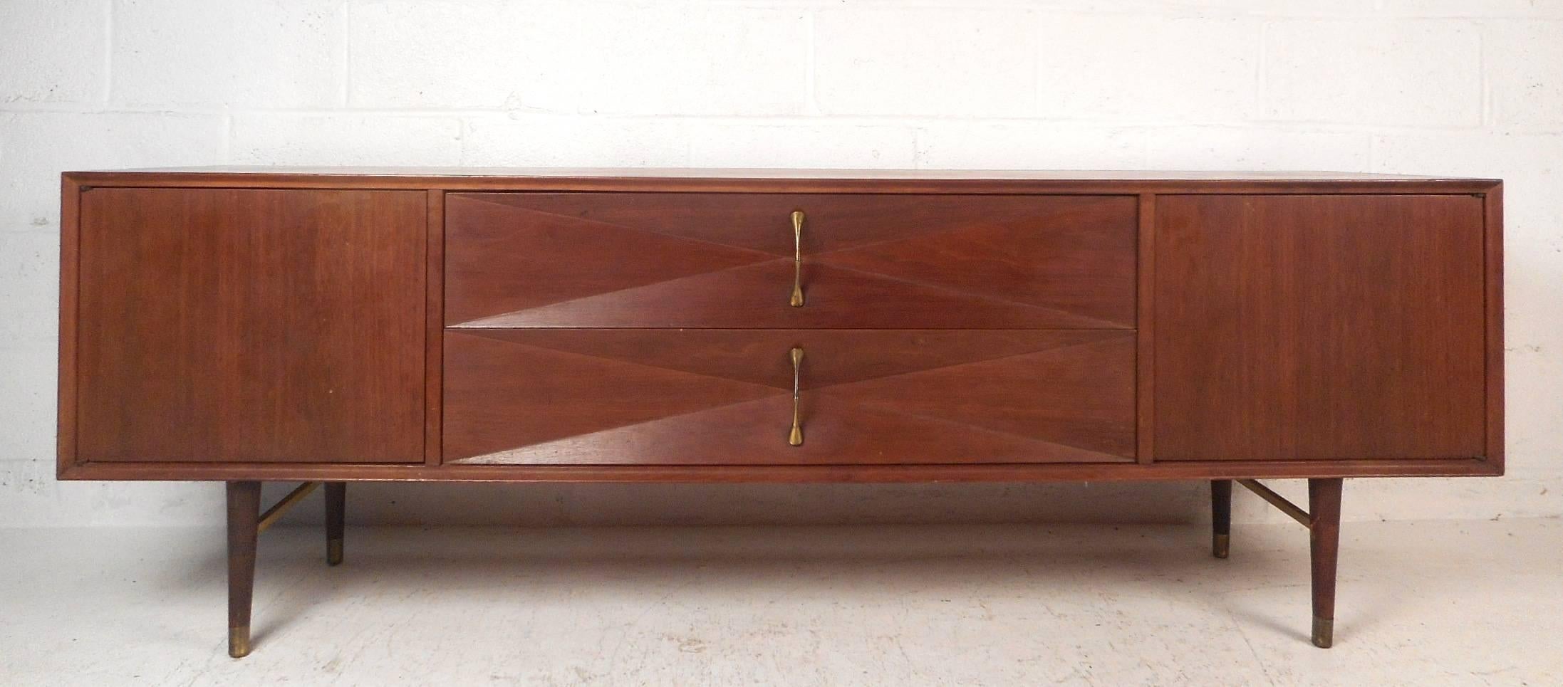 This beautiful vintage modern sideboard features two large drawers with three dimensional diamond fronts and unusual sculpted brass pulls. This unique case piece offers plenty of room for storage within its drawers and two large storage compartments