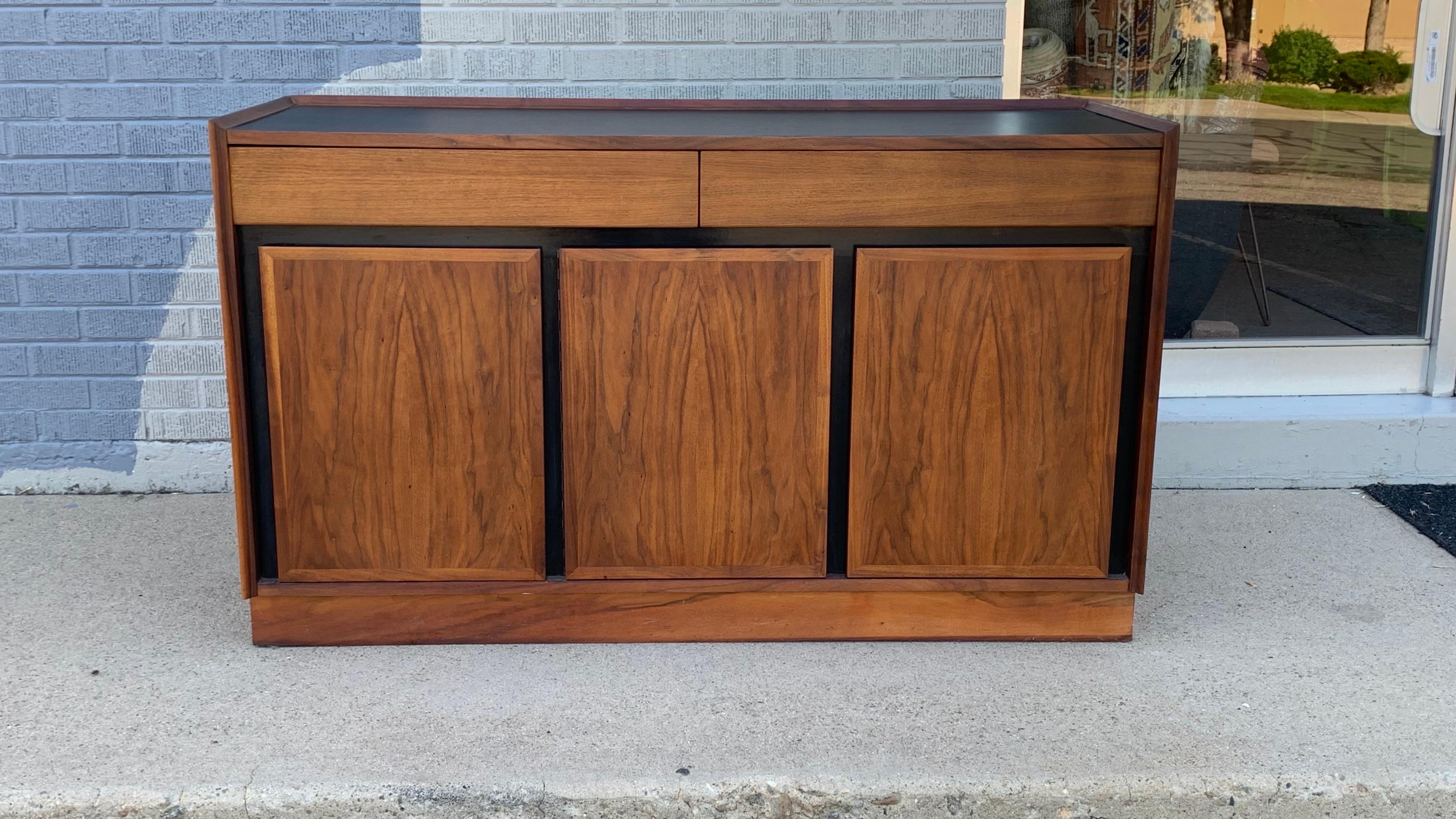 Credenza Dillingham moderna di metà secolo vintage

Questa squisita credenza di Dillingham incarna il design moderno di metà secolo con le sue linee pulite, la ricca impiallacciatura in noce e le sorprendenti finiture nere. Con due cassetti