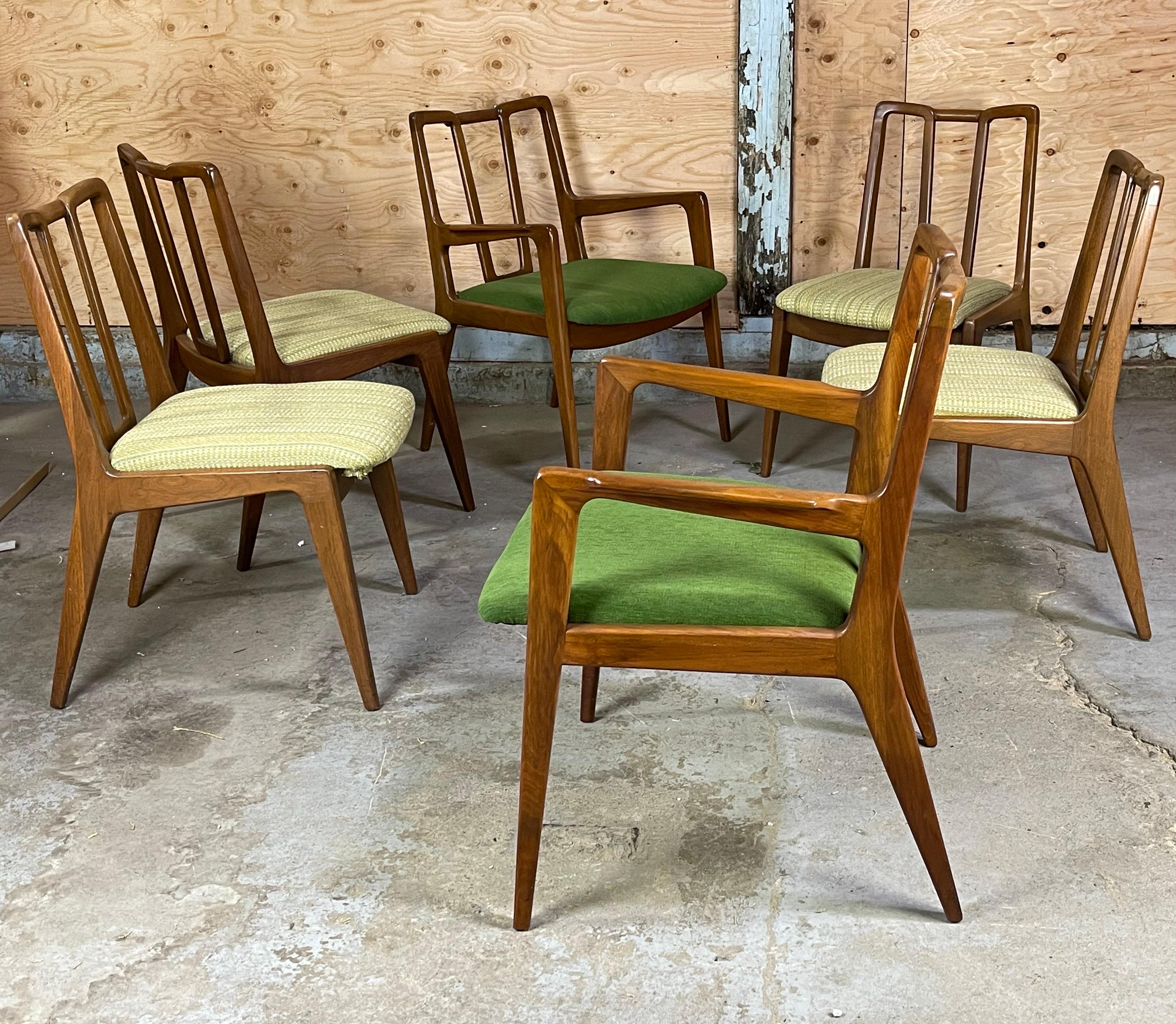 Lovely sculpted walnut Mid Century dining chairs after Ico Parisi or James Mont. Original condition. Reupholstered seat cushions in emerald green for the Capt chairs and a striped vintage tweed in an array of greens on the side chairs. Wear mostly