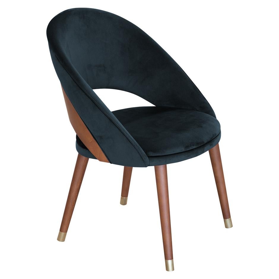 Mid-Century Modern dining chairs upholstered in black velvet. 
Crafted of solid wood frame stained in walnut finish. 
Curved back for greater support and comfort to enjoy long dinners.
Rounded brass metal caps.
This chair is heavily constructed and