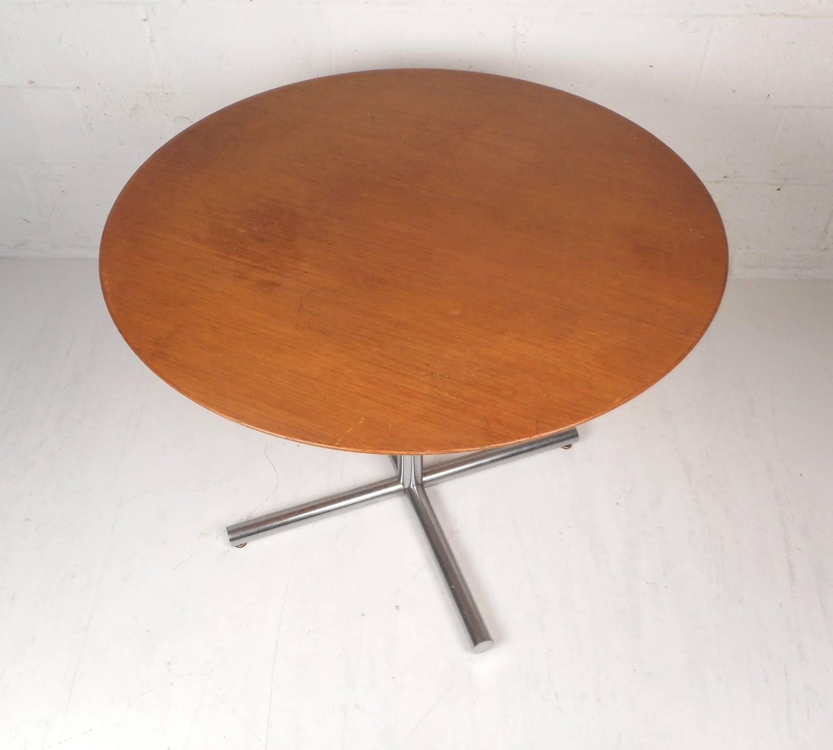 This unique vintage modern table functions as a kitchen table, a card table, or a dining table. Sleek design with gorgeous wood grain on the top and a heavy chrome base. This wonderful midcentury piece has one large cylindrical chrome support