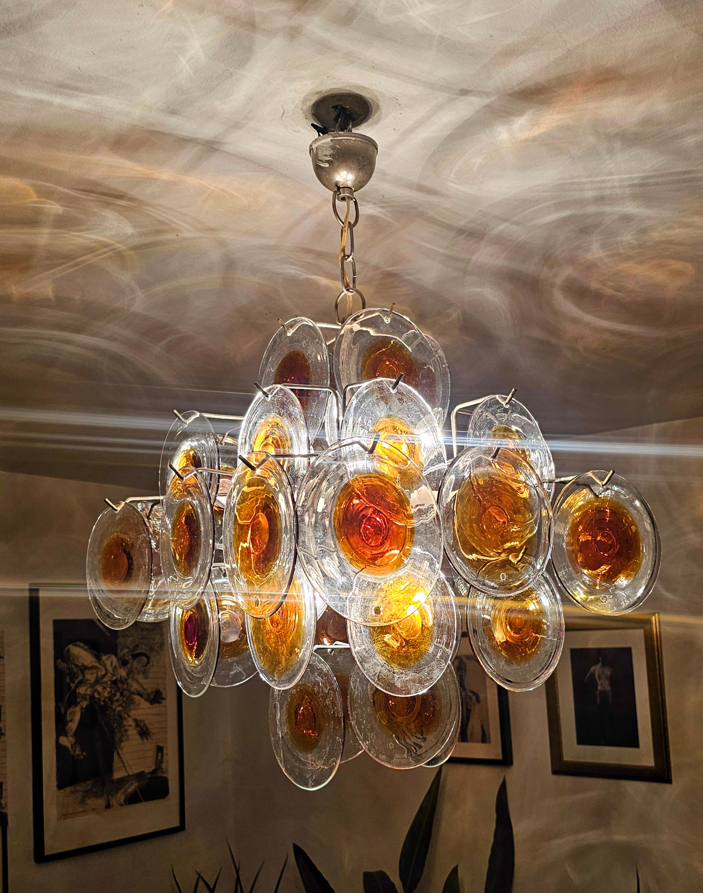 In this listing you will find a gorgeous, iconic chandelier designed by Gino Vistosi. It features 36 Murano glass discs in amber and clear glass, which provide beautiful light patterns when the lights are on. Made in Italy in 1960s.

Very good