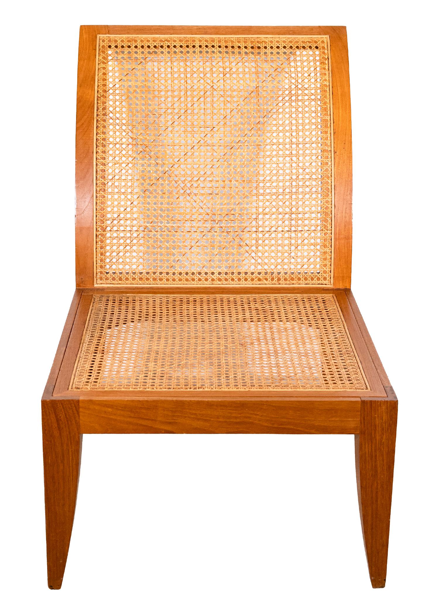 A Donghia rattan cane Jeanerret style chair. This unique accent chair has an incredible silhouette with its long, arching back, and its matching pointing legs. The chair is constructed with solid wood that has a semi-gloss finish, and a stunning