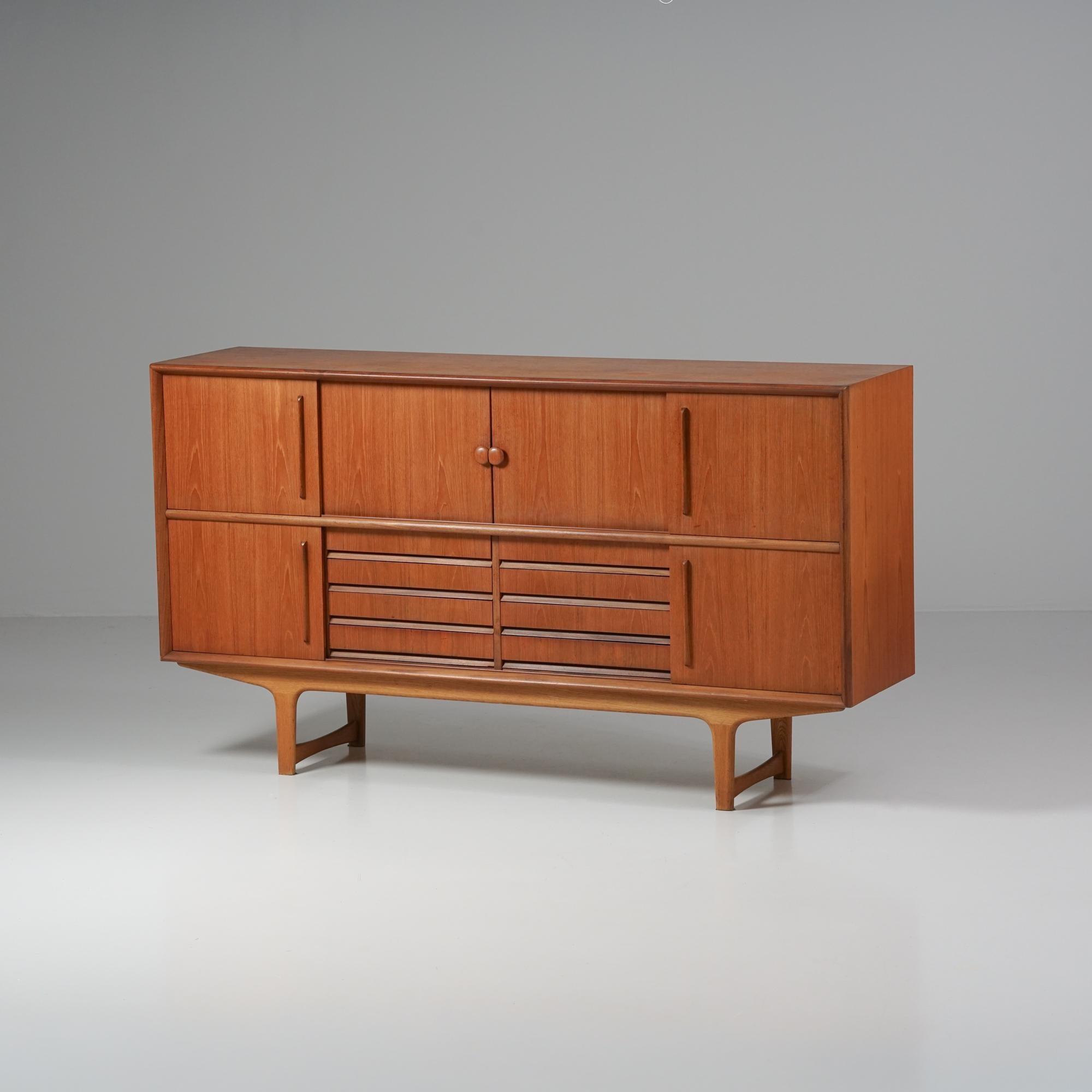 Mid-Century Modern double sideboard, manufactured in Denmark, 1960s.  Teak with oak legs. Shelves on both sides. Eight drawers at the bottom and shelves at the top. Quality craftmanship. Good vintage condition, patina consistent with age and use. 

