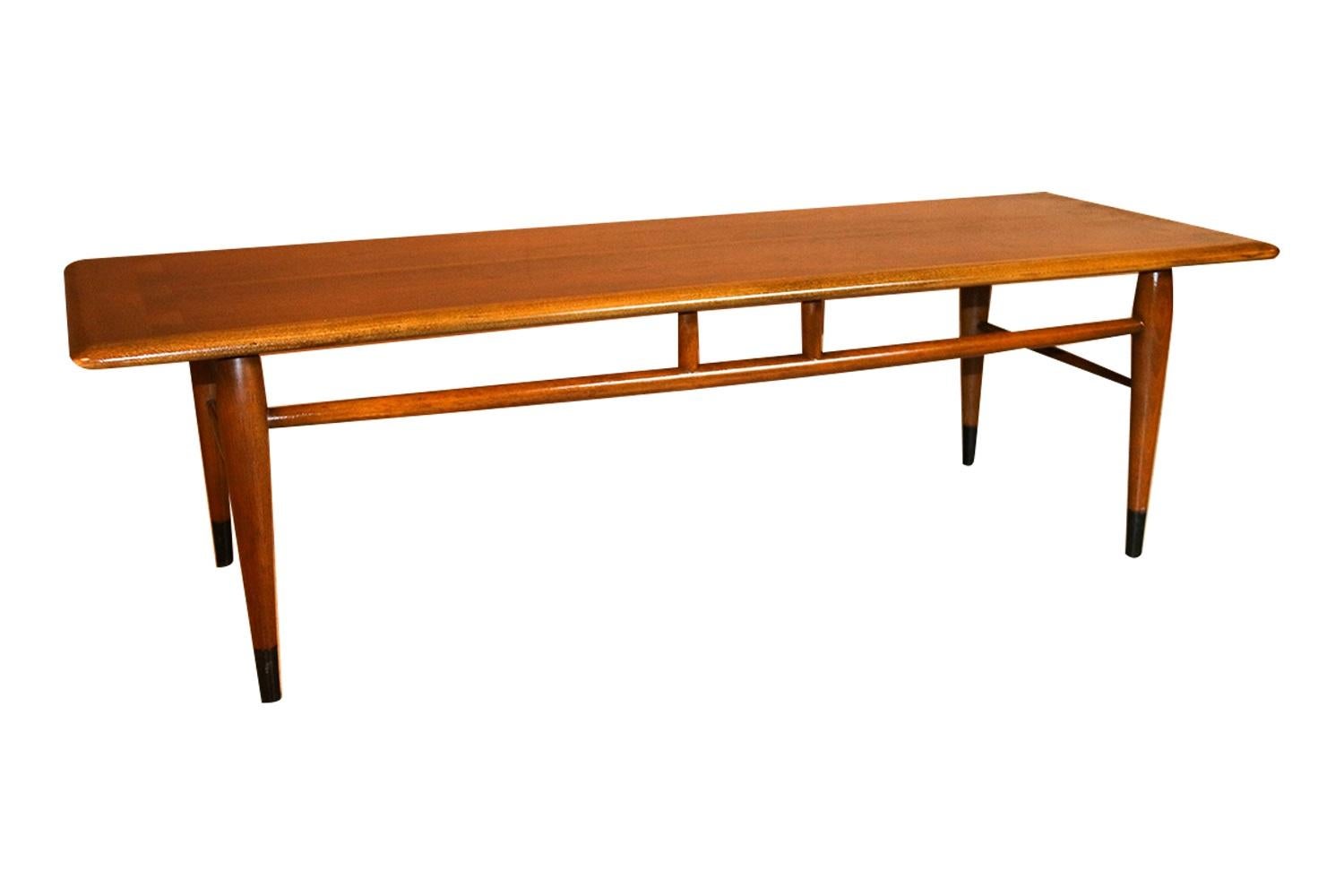 An American walnut and oak coffee table. This Mid-Century Modern coffee table in walnut veneered and solid oak was made in Altavista, VA by Lane Furniture (manufacturer). It has the contrasting dovetail detail on the top that identifies it as part
