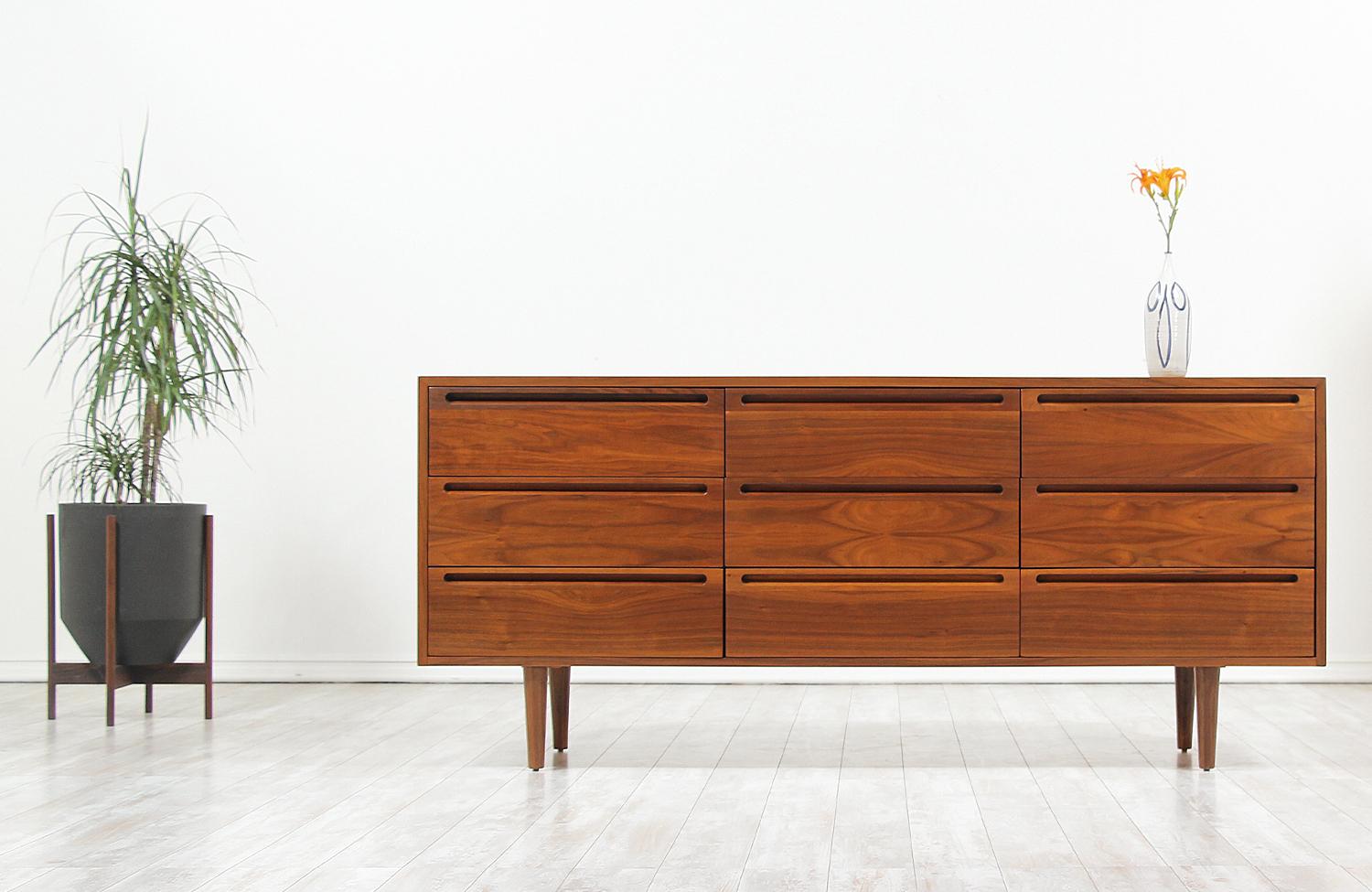 Beautiful Mid-Century Modern long dresser designed and manufactured by American of Martinsville in the United States, circa 1960s. This nine drawer dresser features a walnut wood frame with sculpted handles and a beautiful warm grain detail that