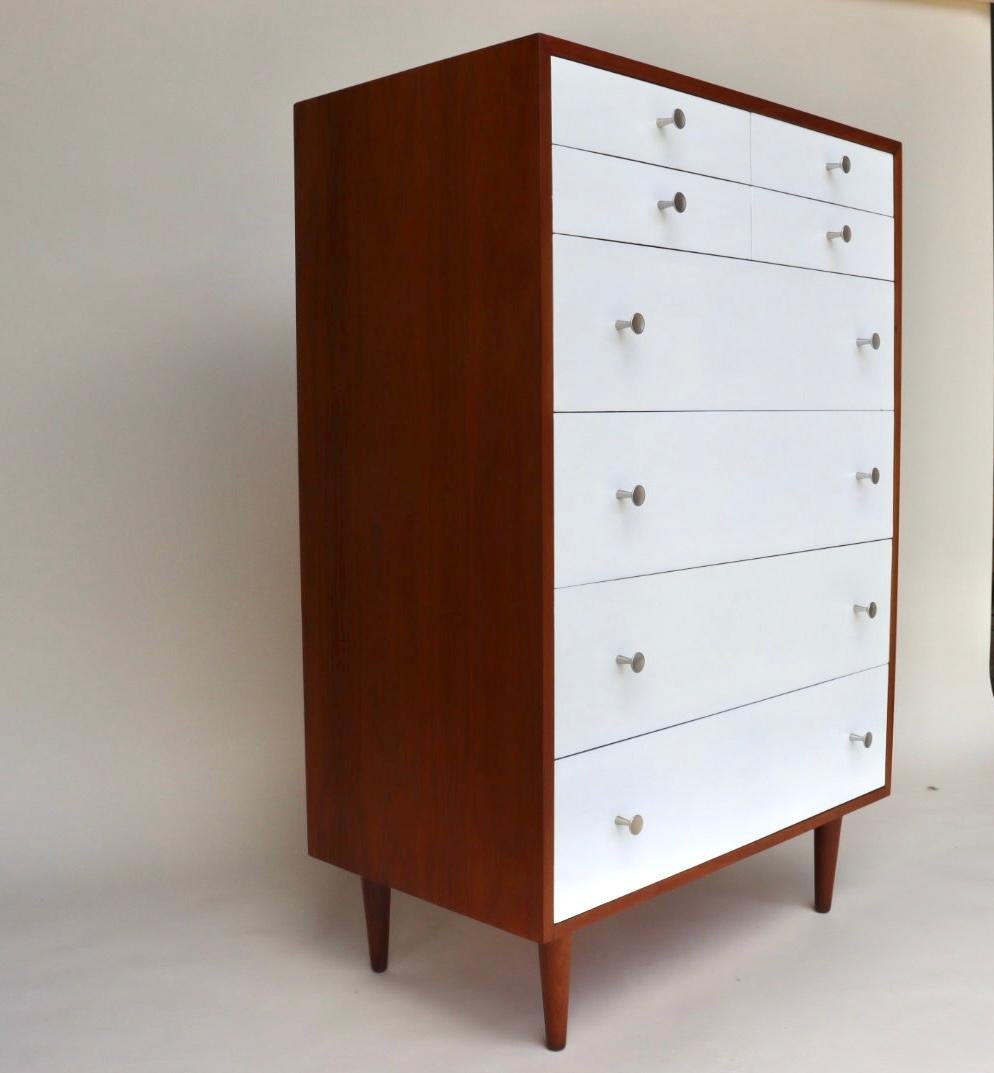 This is a rare Glenn of California tall dresser designed by Kipp Stewart and Stewart MacDougall circa 1960's. This dresser has been executed in walnut with exquisite hourglass hardware. This dresser features white lacquered drawer fronts in a glossy
