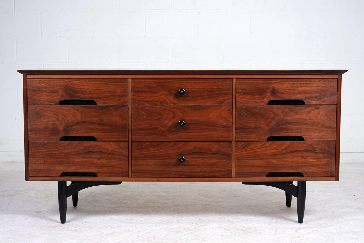 This 1960s Mid-Century Modern-style Dresser is made out of walnut wood and has been beautifully stained in a rich walnut color with a newly lacquered finish. This modern chest of drawers features a sturdy nine drawers with carved ebonized handles &