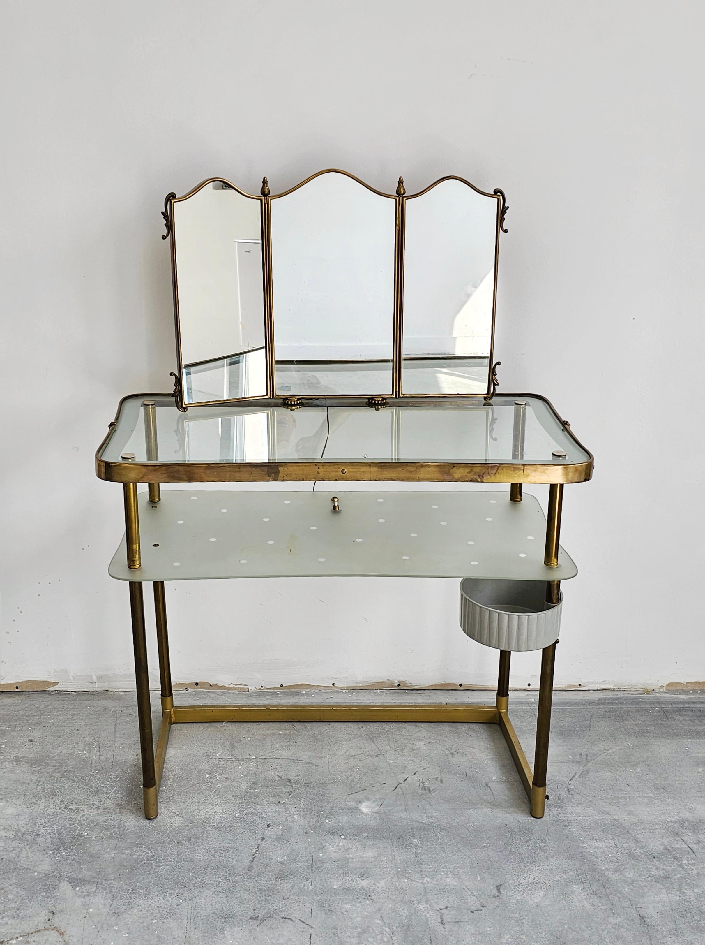 In this listing you will find an extremely elegant Mid Century Modern Vanity Table with a Triptych Mirror done in bronze and glass. Table is designed by Luigi Brusotti. It features a single light bellow the polka dot shelf. Made in Italy in