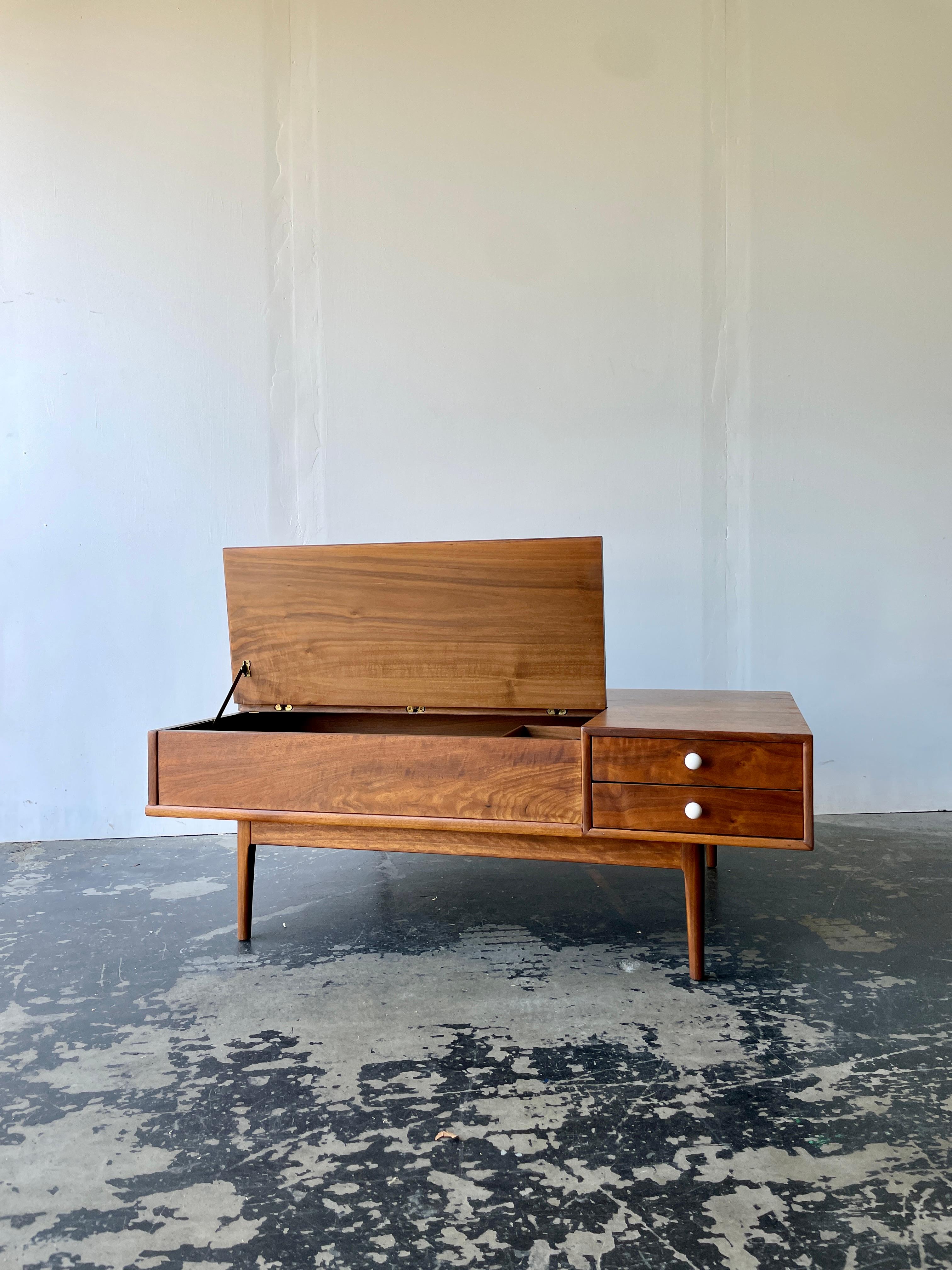 This glowing walnut coffee table designed for Drexel Declaration has the iconic white porcelain hardware and long elegant legs that make the  series so popular. Marrying beauty with great functionality, this table is open on both sides. One side has