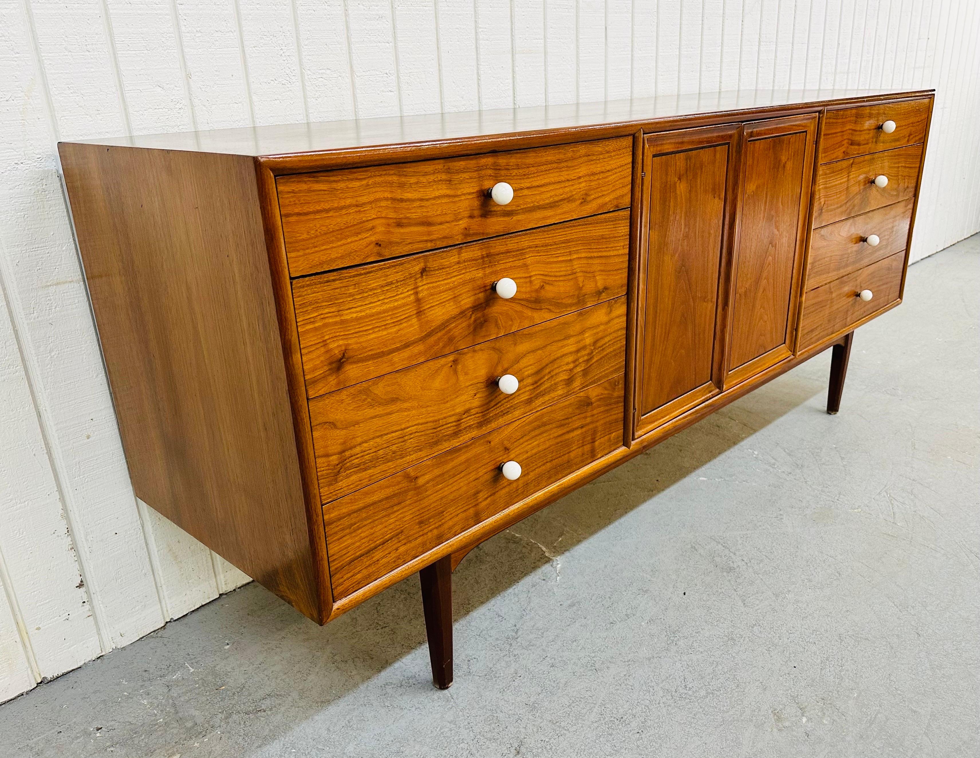 This listing is for a Mid-Century Modern Drexel Declaration Walnut Dresser. Featuring a rectangular design, two center doors that open up to three hidden drawers, eight drawers with original white knobs, and a beautiful walnut finish. This is an